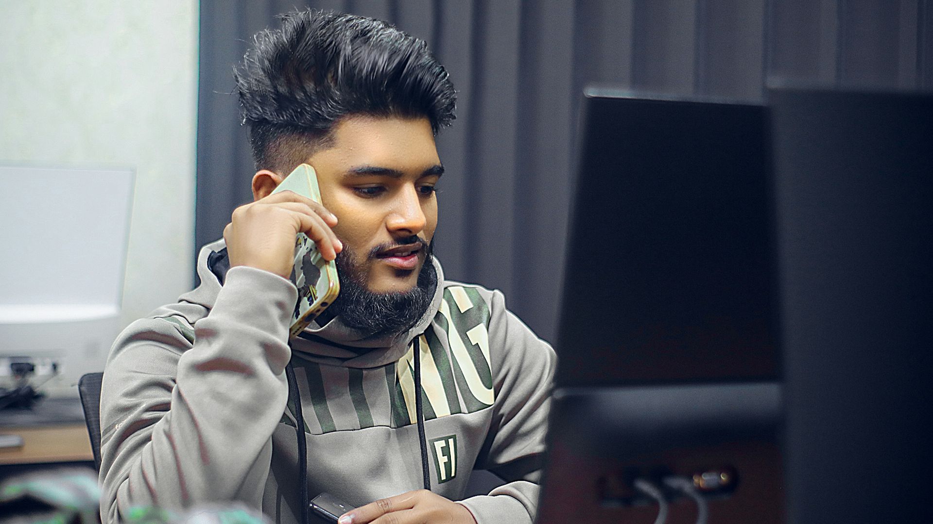 Man is on the phone in front of computer.