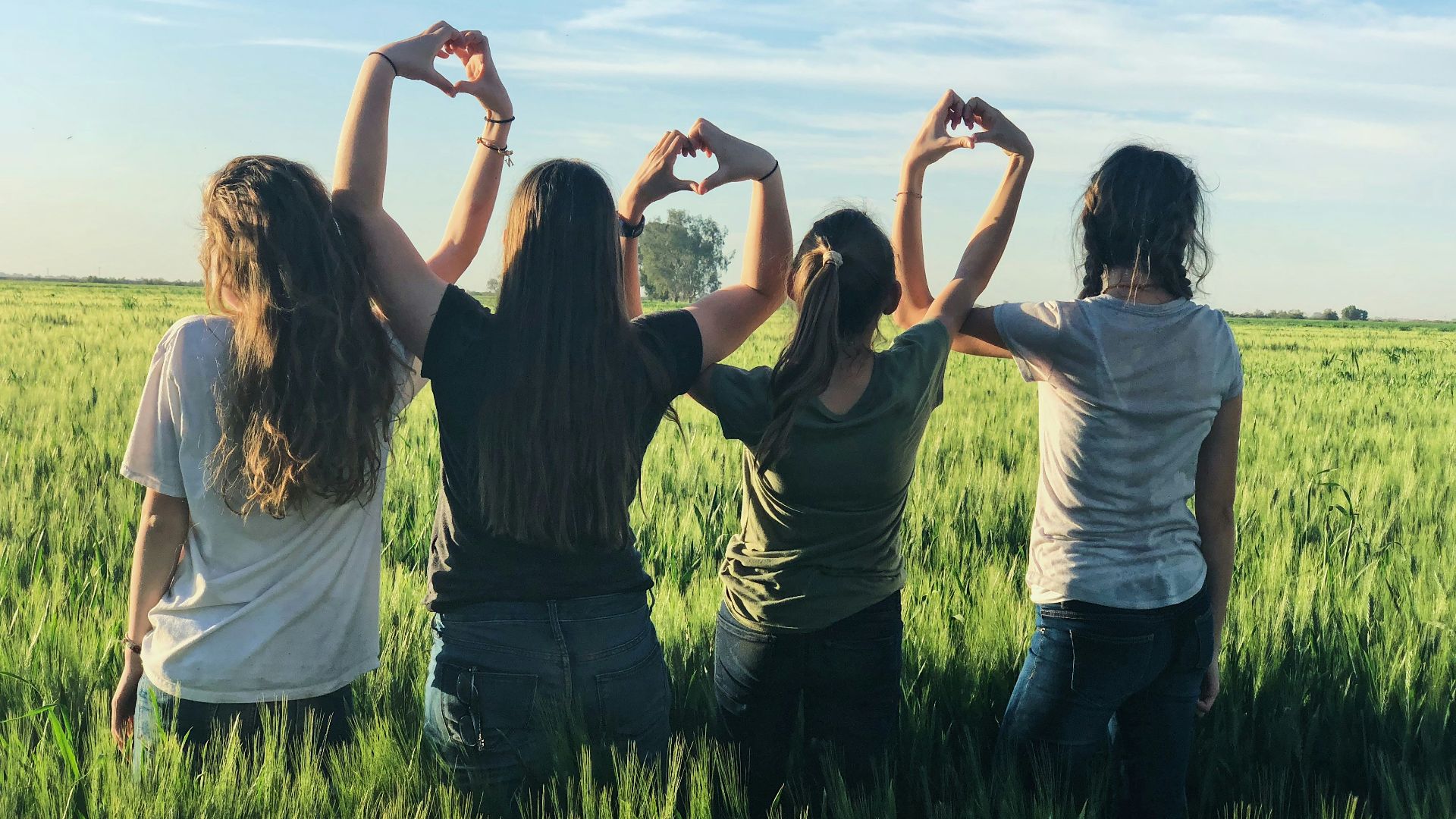 women forming heart gestures during daytime