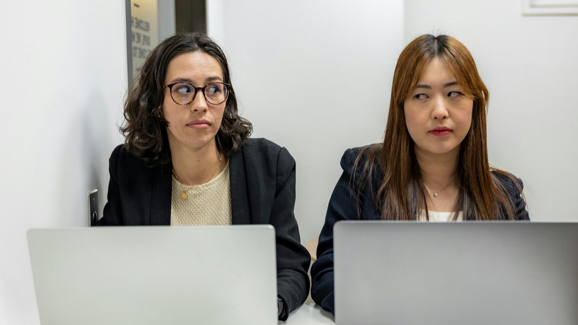 two women sitting at a table with laptops