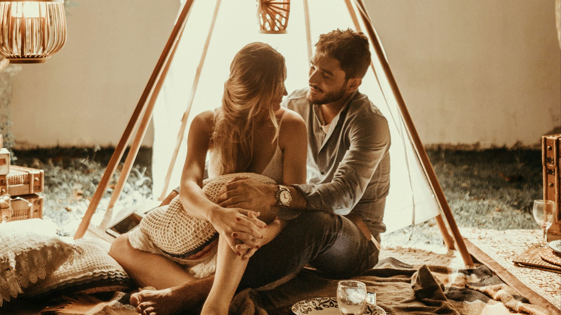 couple sitting inside tepee hut with lights