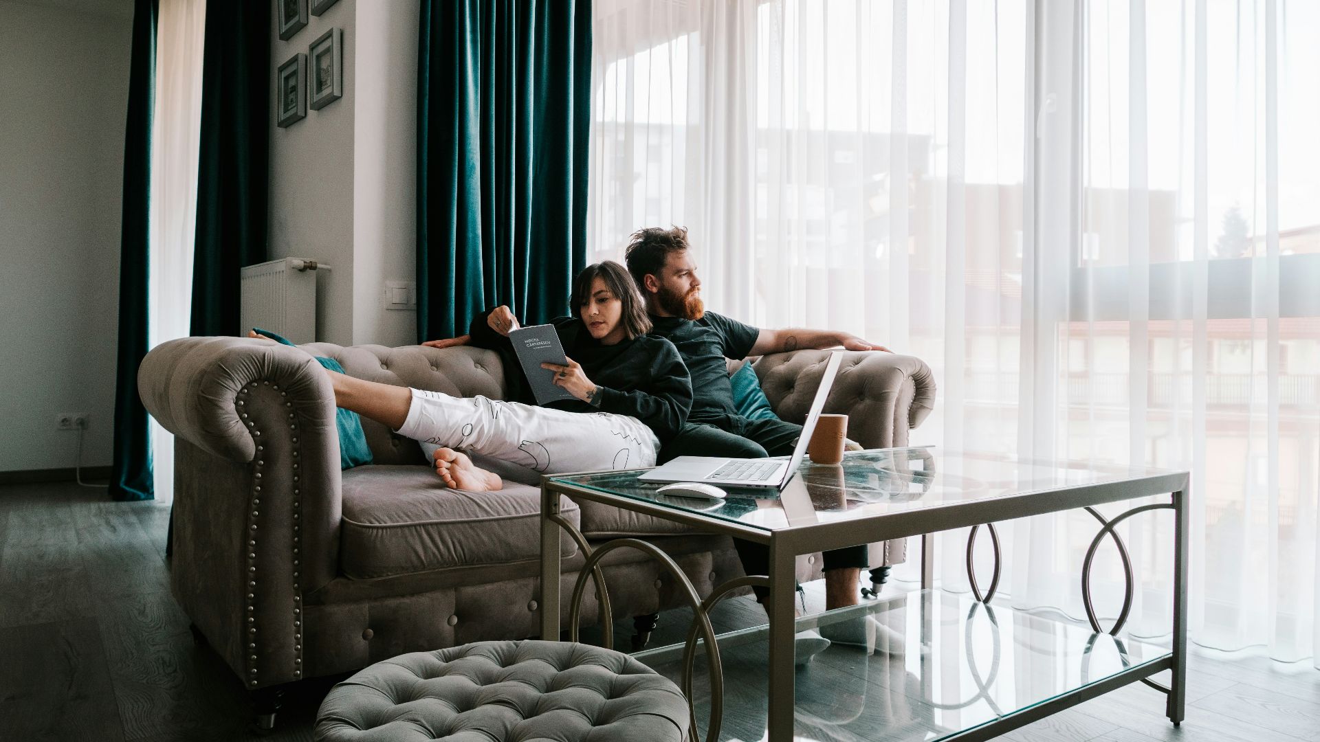 2 women sitting on sofa near window