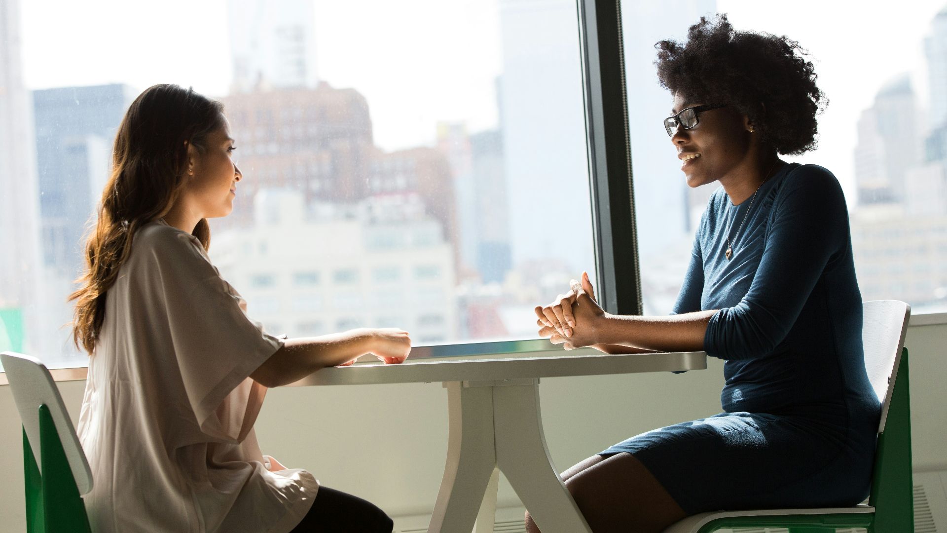 two women sitting beside table and talking