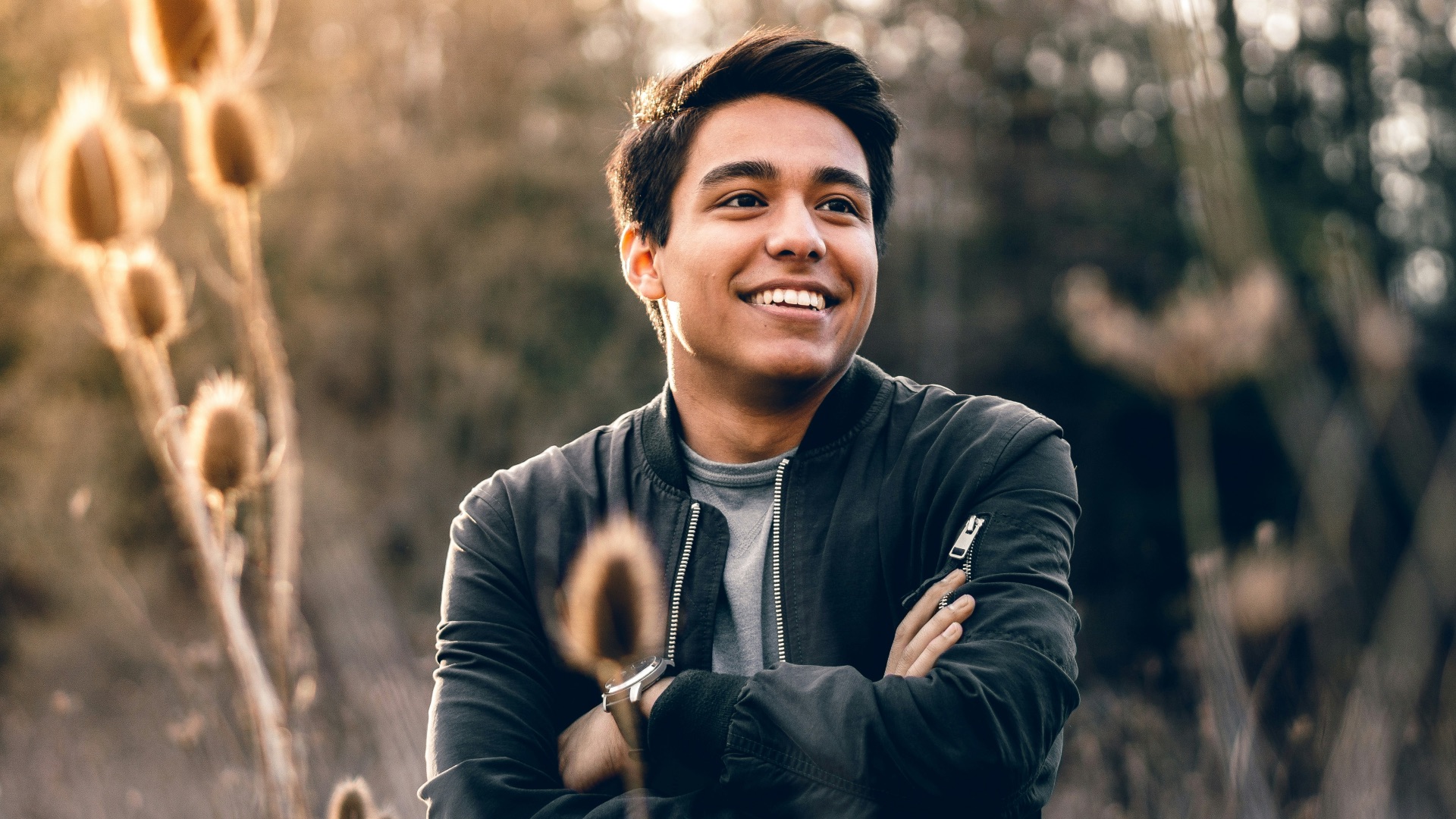 smiling man standing near green trees
