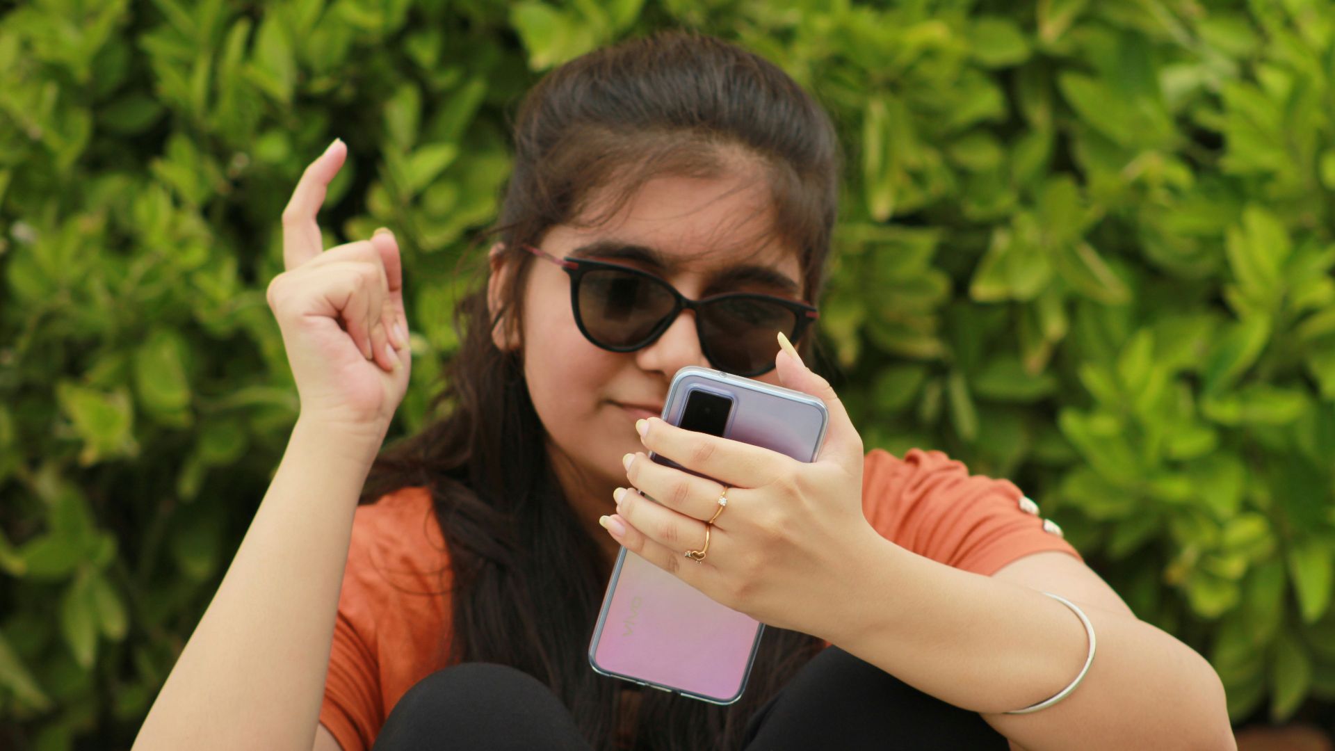 a woman sitting on the ground holding a cell phone