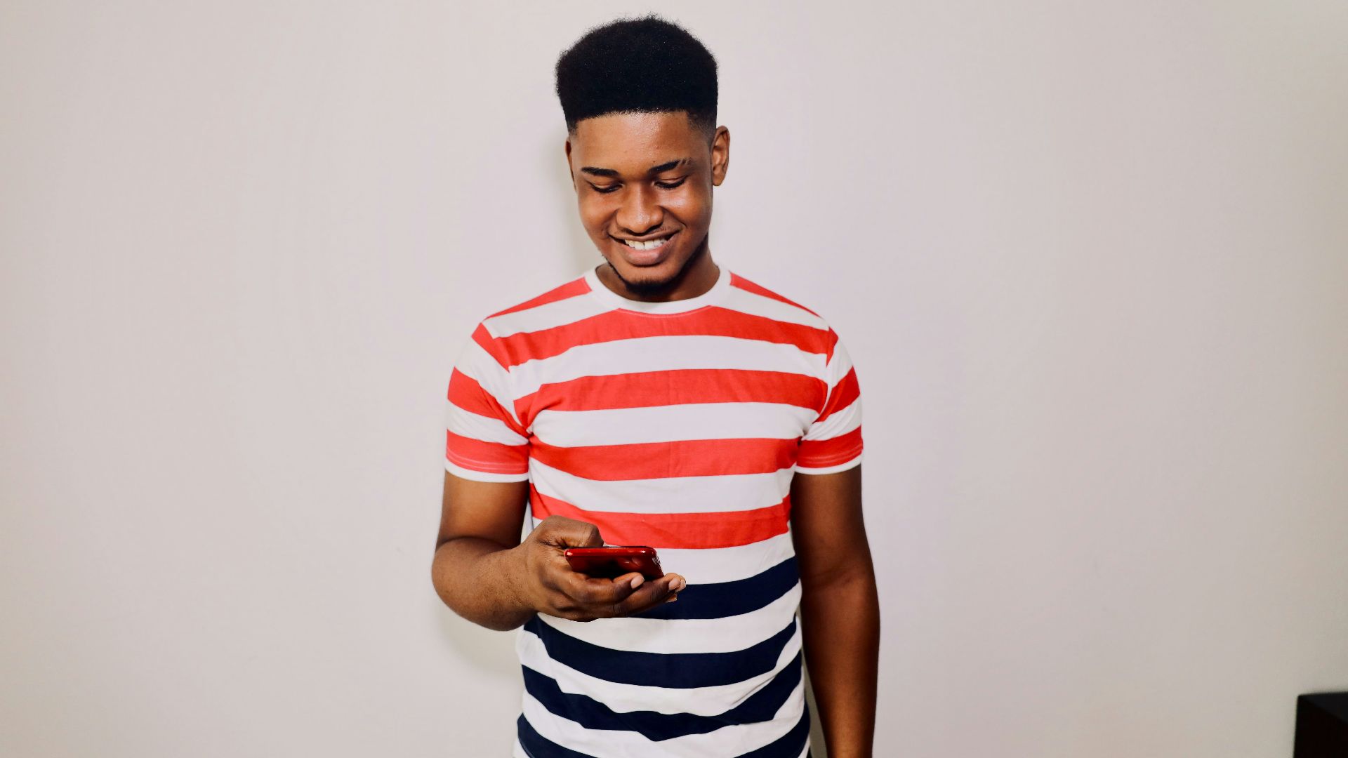 a man in striped shirt holding a cell phone