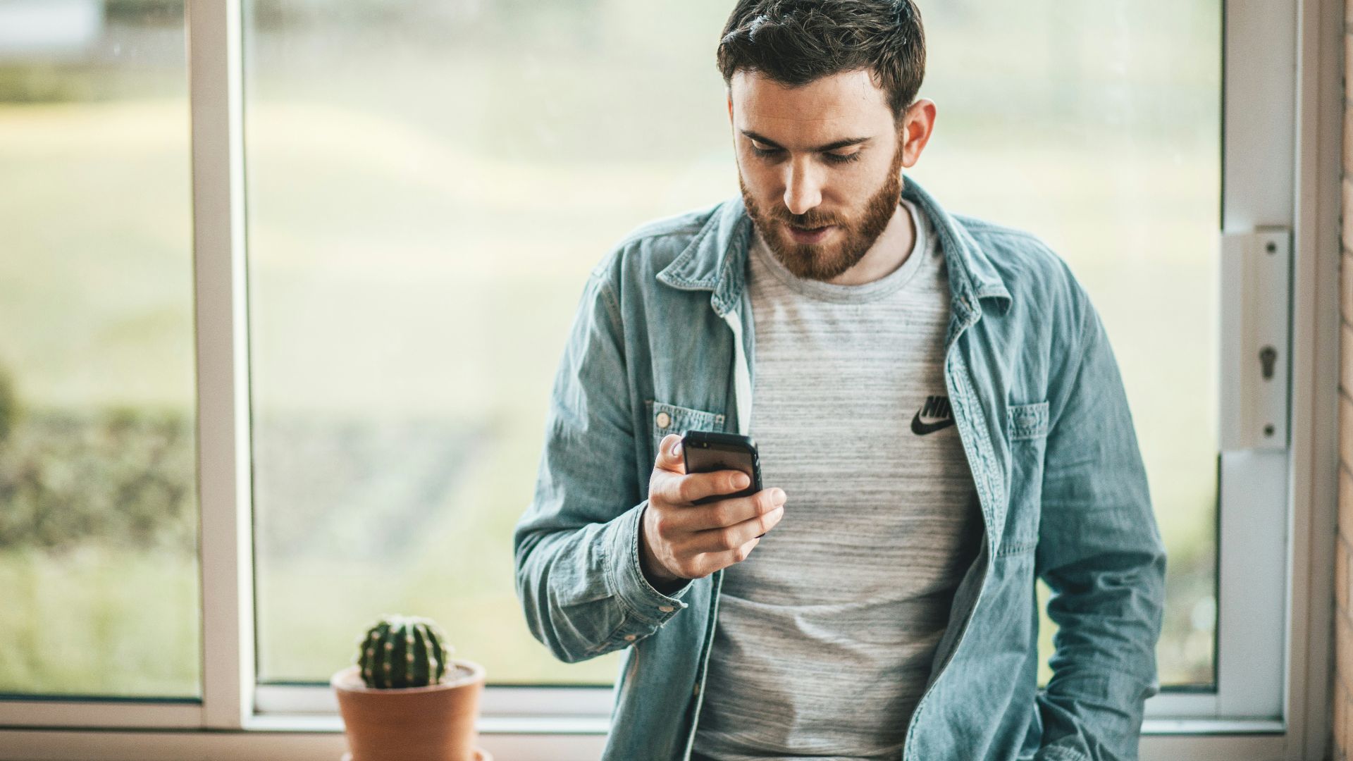man holding a smartphone near the window