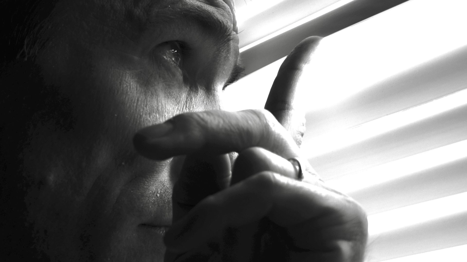 Man looking through window blinds