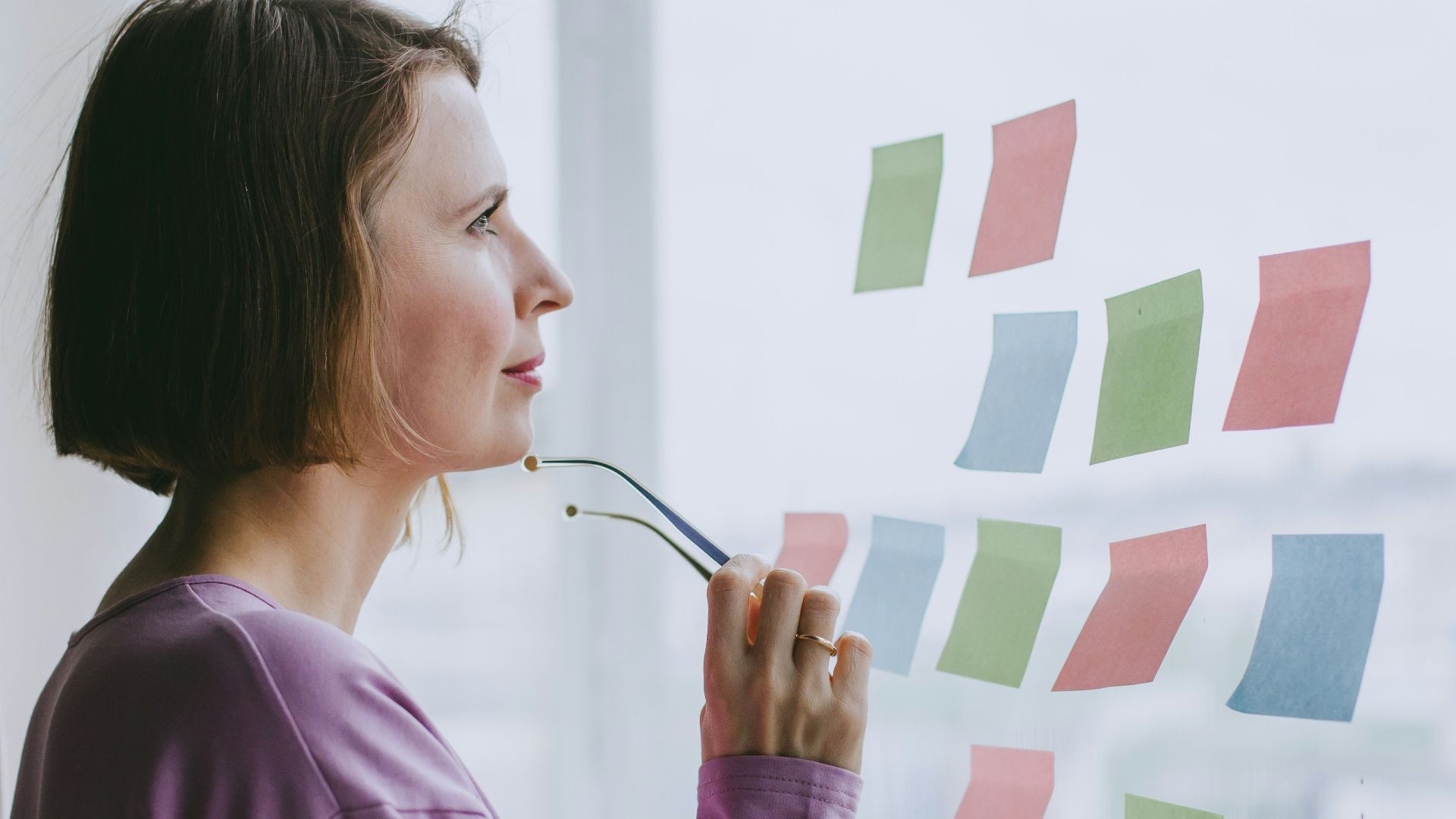 a woman looking out a window with sticky notes on it