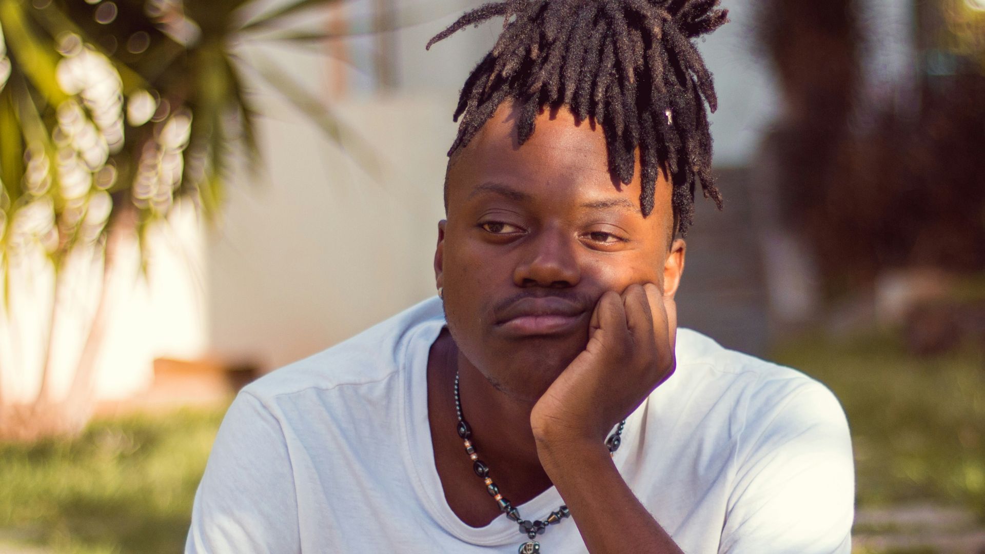 man in white crew neck t-shirt sitting on brown wooden chair