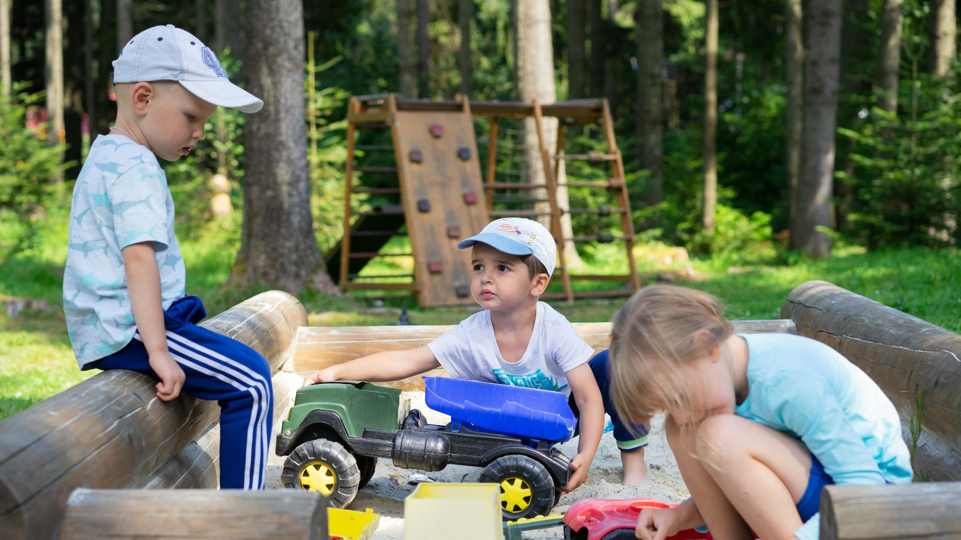 2 boys sitting on red and black ride on toy car