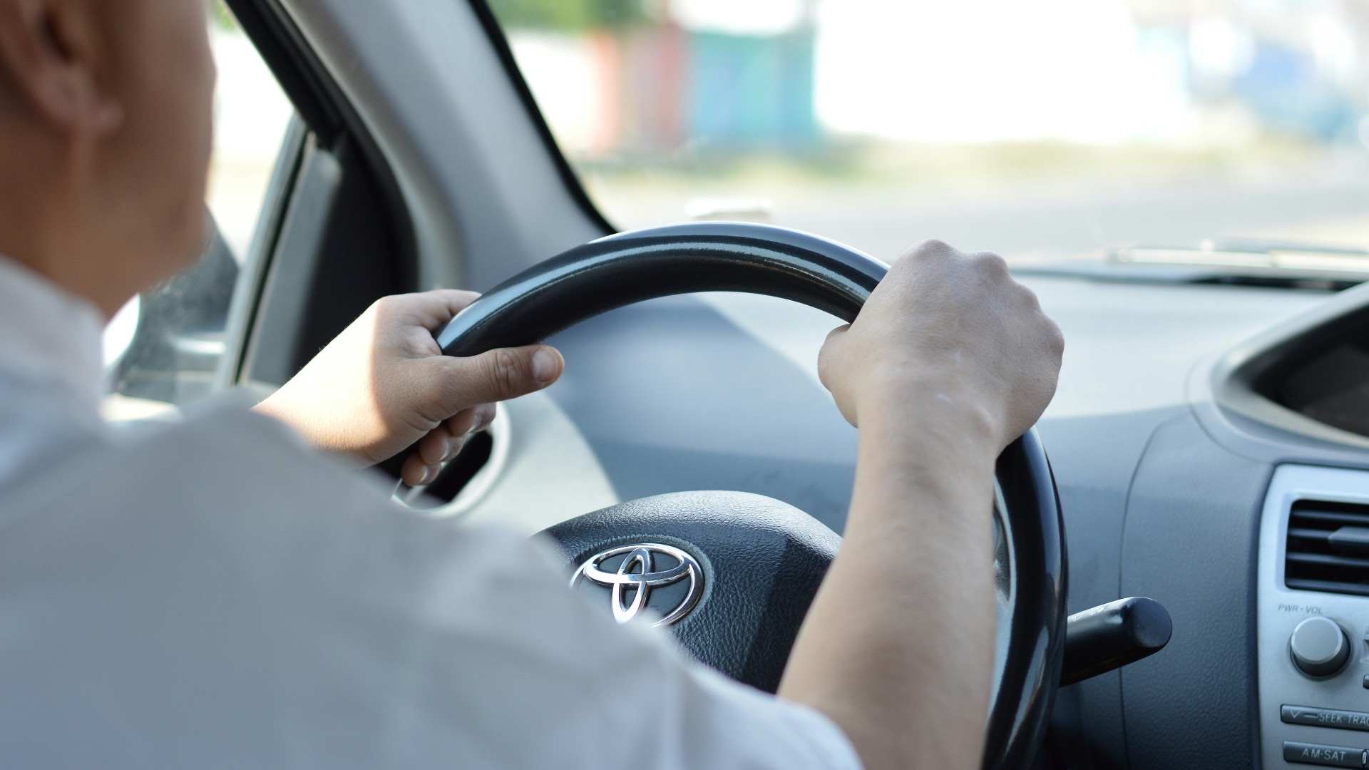 person in white long sleeve shirt driving car