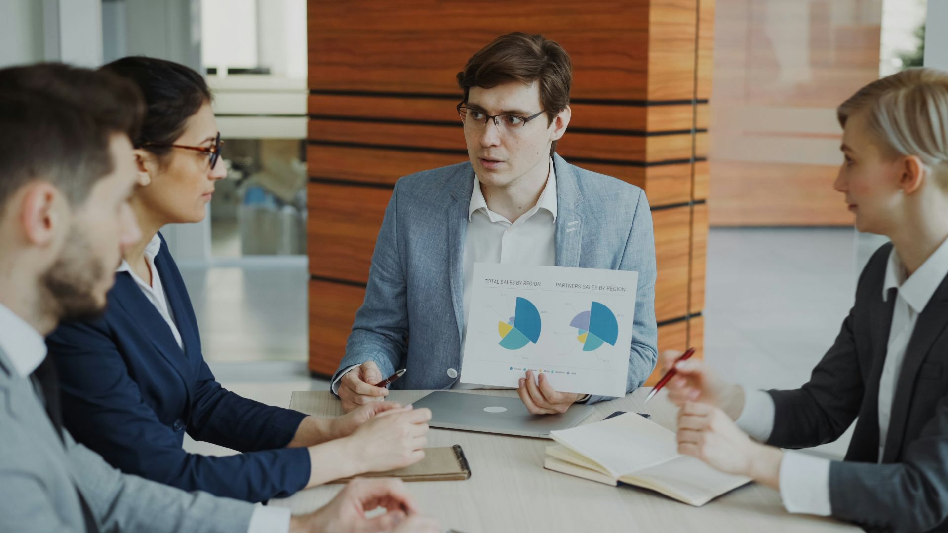 Man presenting charts to colleagues in a meeting.