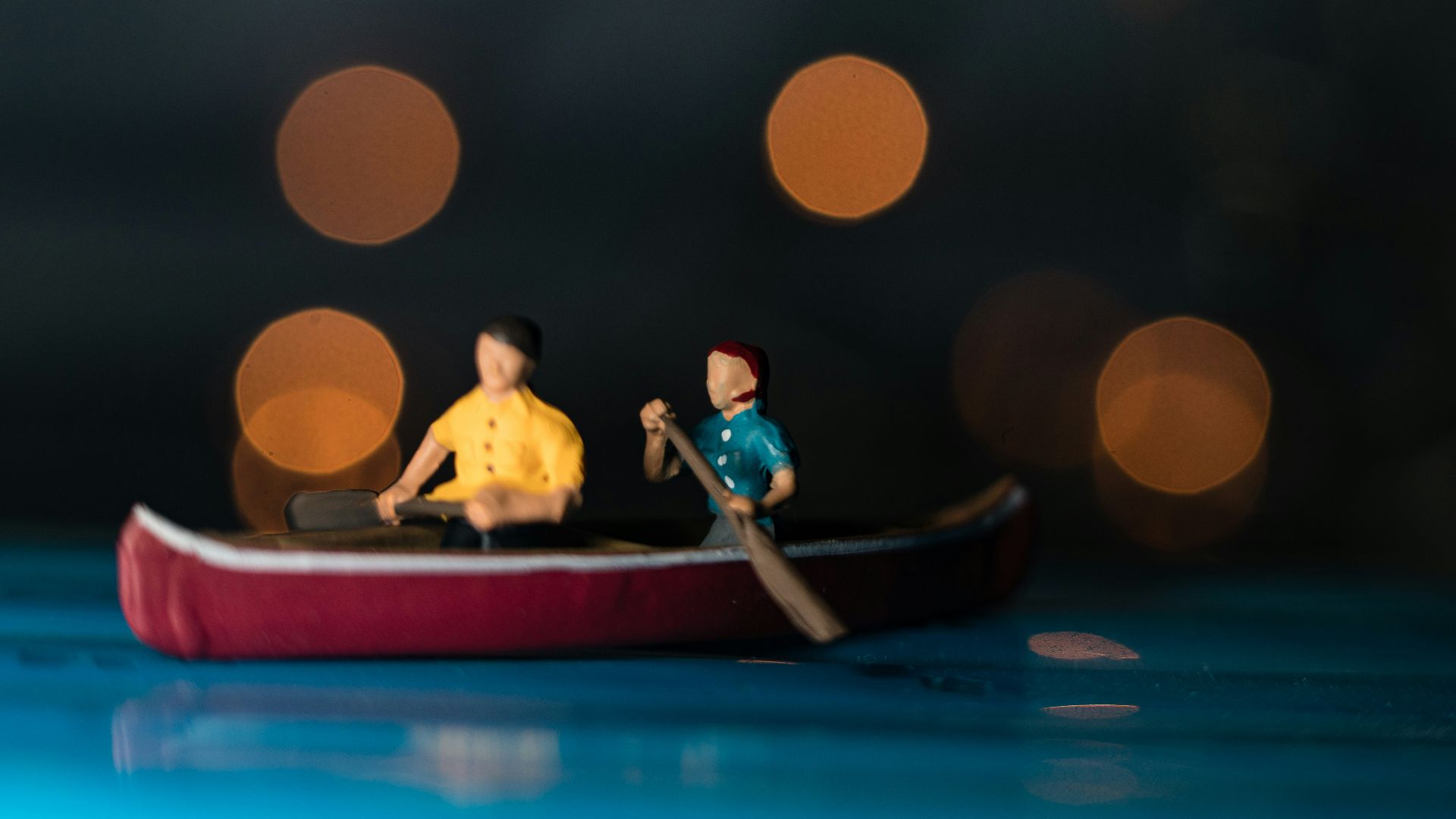 bokeh photography of two men riding canoe scale model