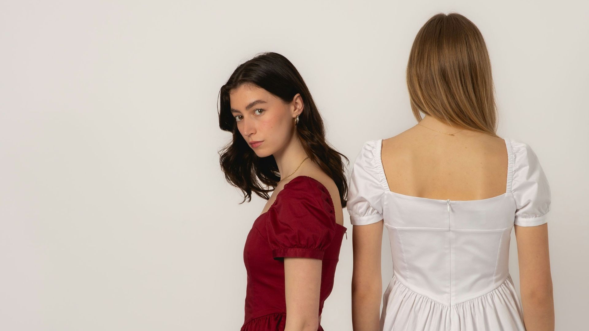 Two young women in dresses against a white background