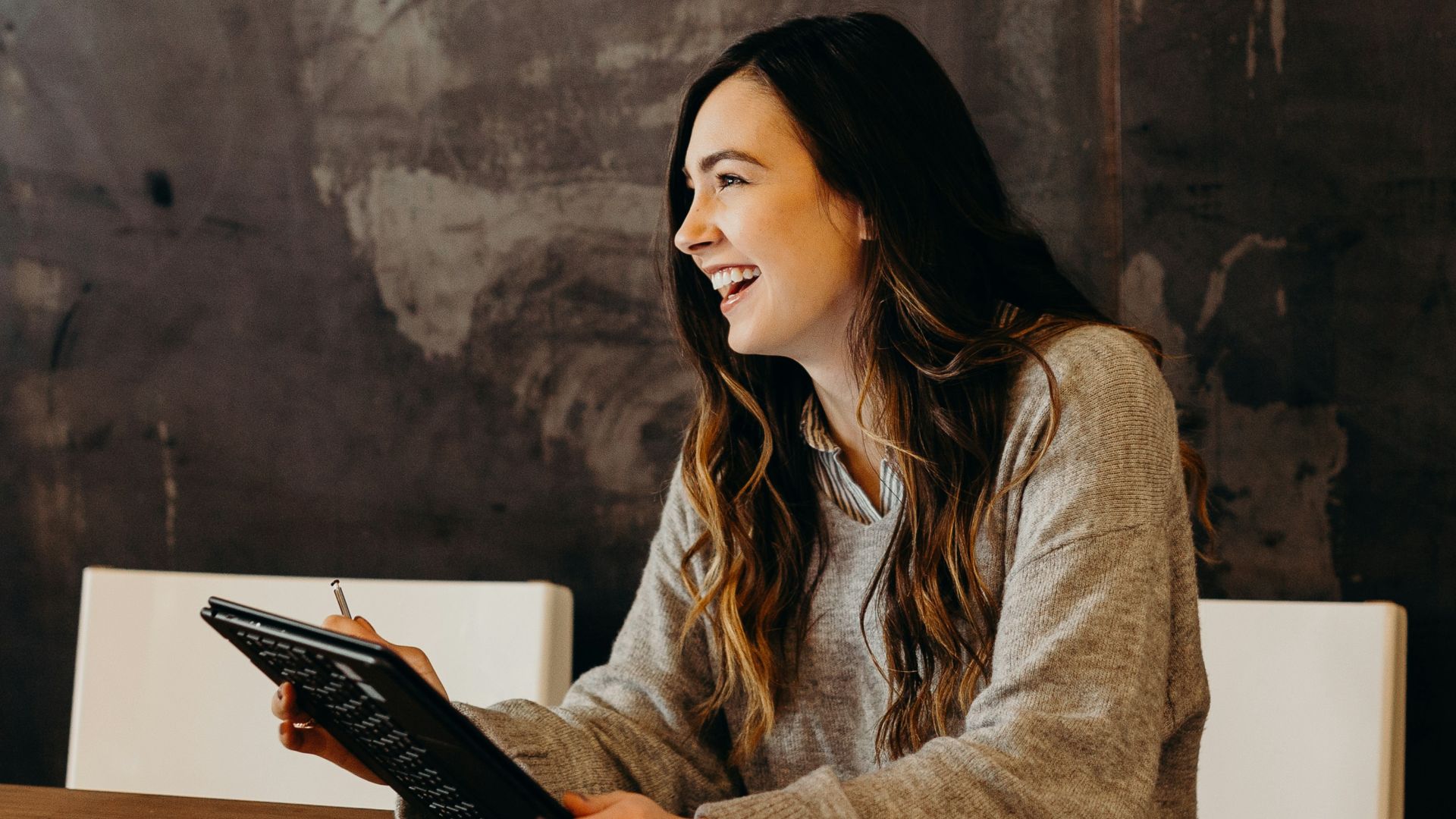 woman sitting around table holding tablet