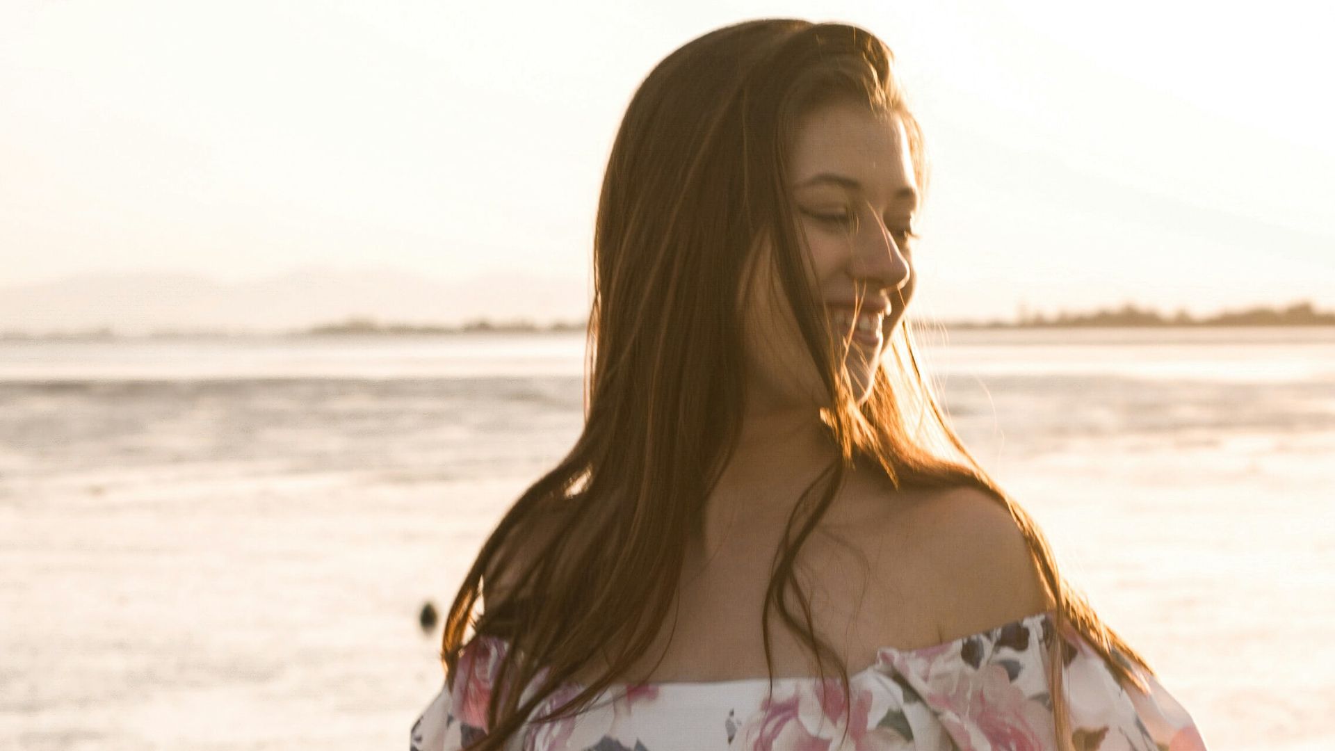 a pregnant woman in a floral dress standing by the water