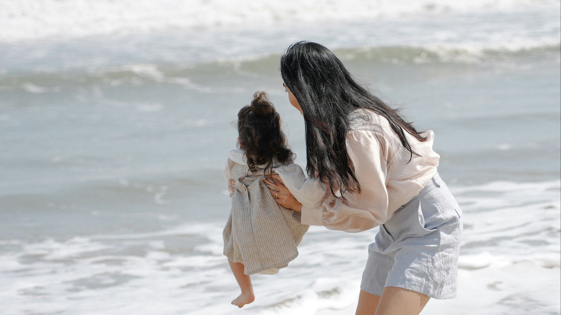 Mother and child playing in the ocean waves