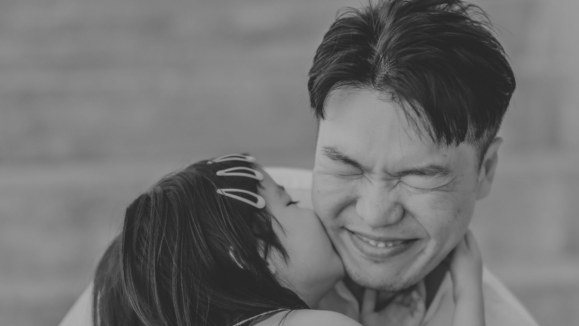 A girl kisses her father on the cheek.
