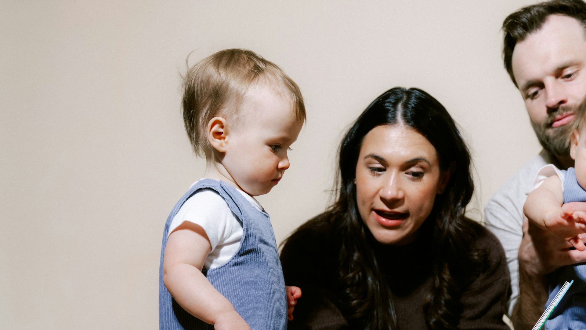 Family reading a book together on a plain background.
