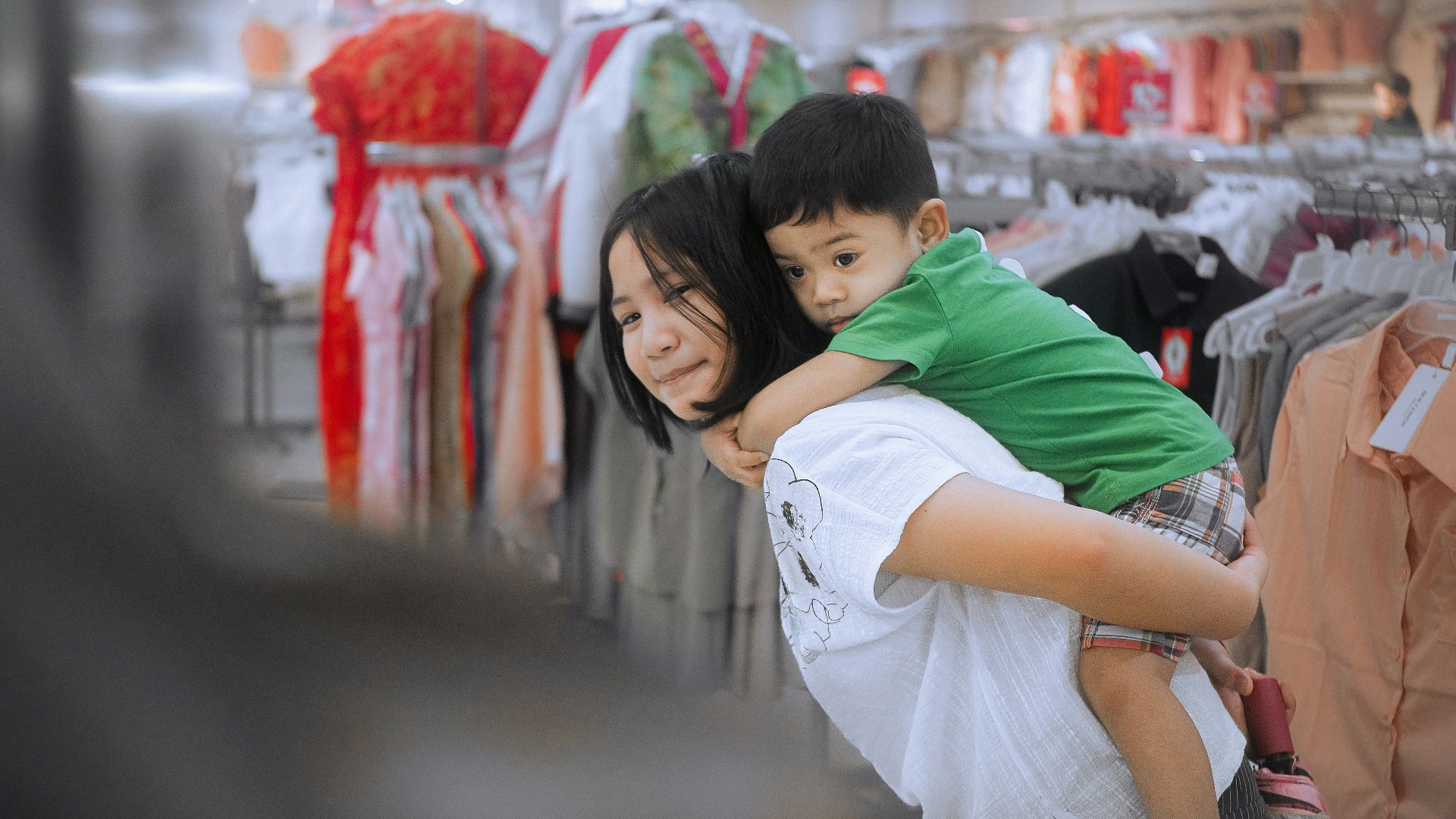 Woman giving a child a piggyback ride in a store.