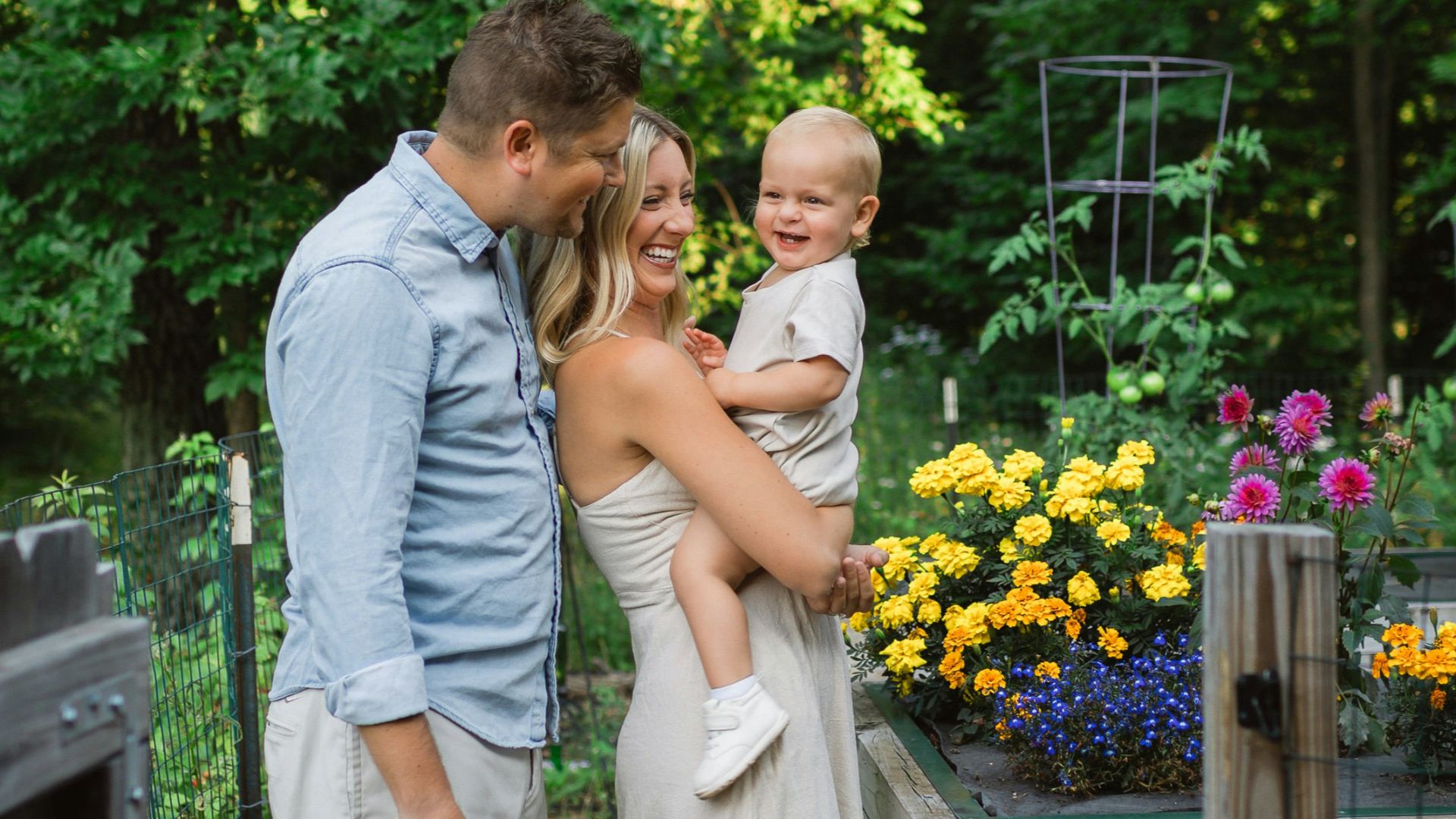 a man and woman holding a baby in a garden