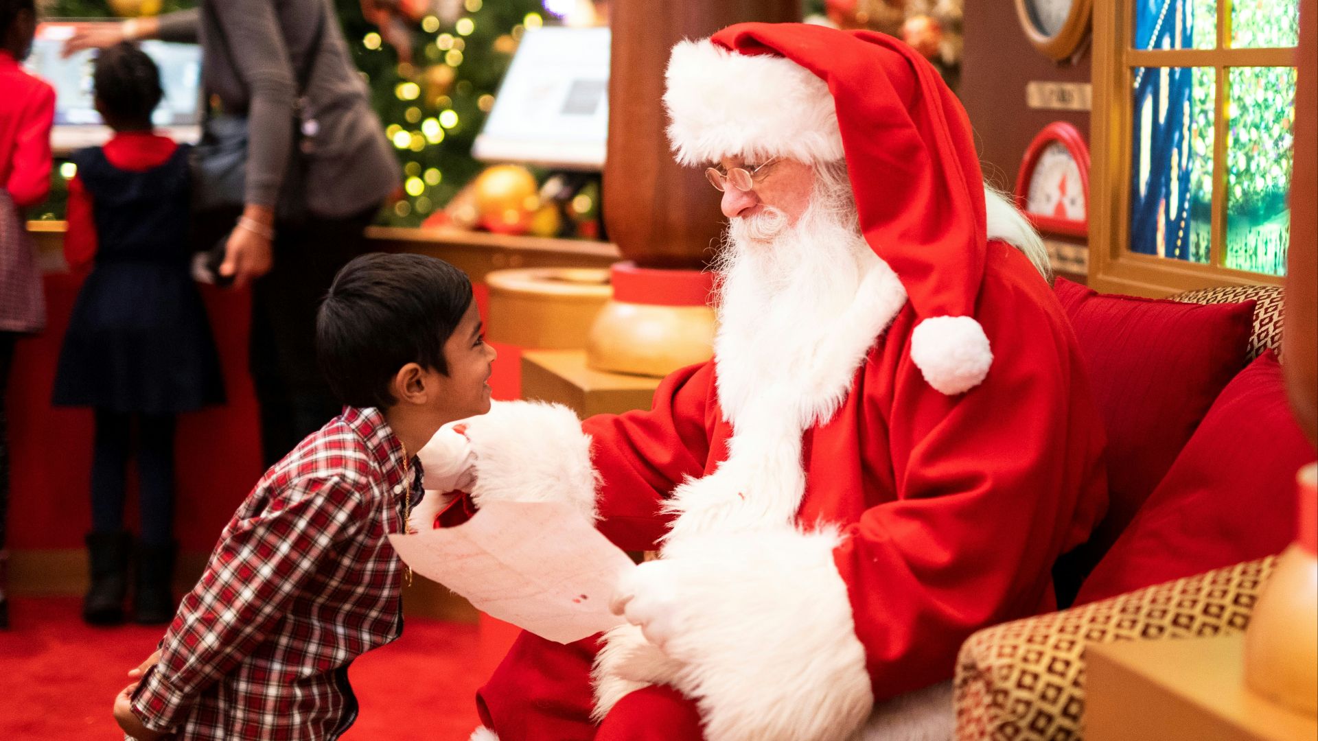boy standing in front of man wearing Santa Claus costume