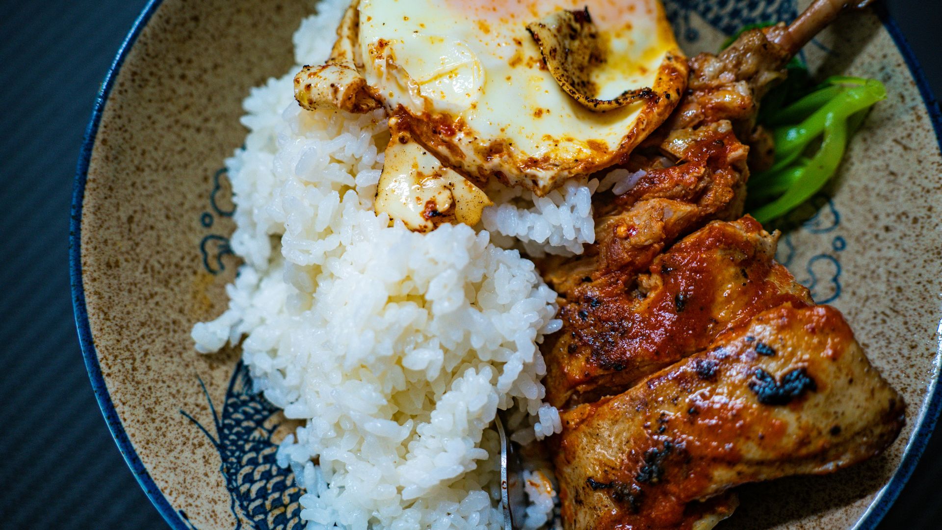 a plate with rice, meat and a fried egg