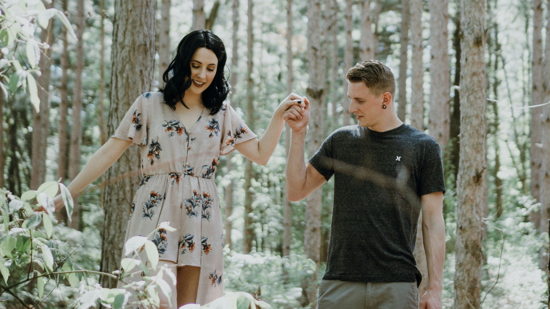 man holding hands with woman near trees