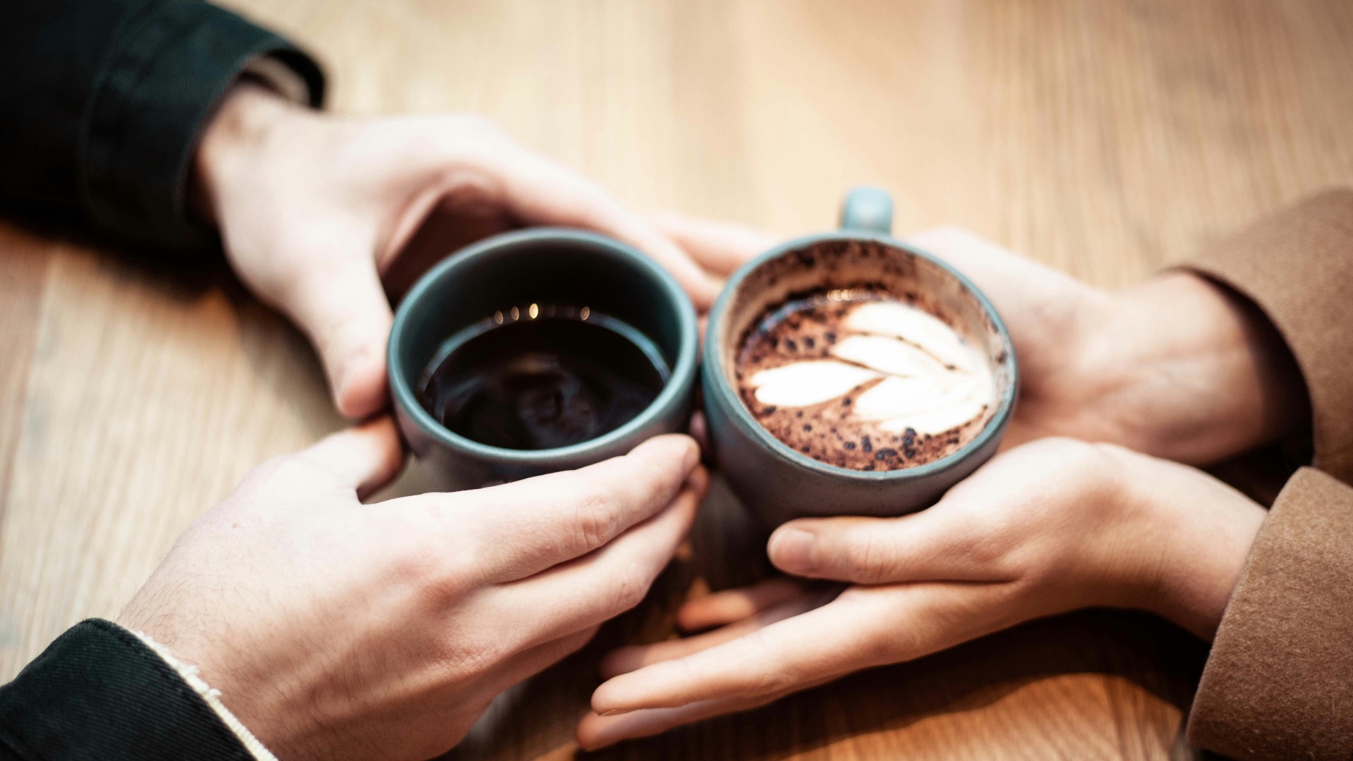two person holding ceramic mugs with coffee