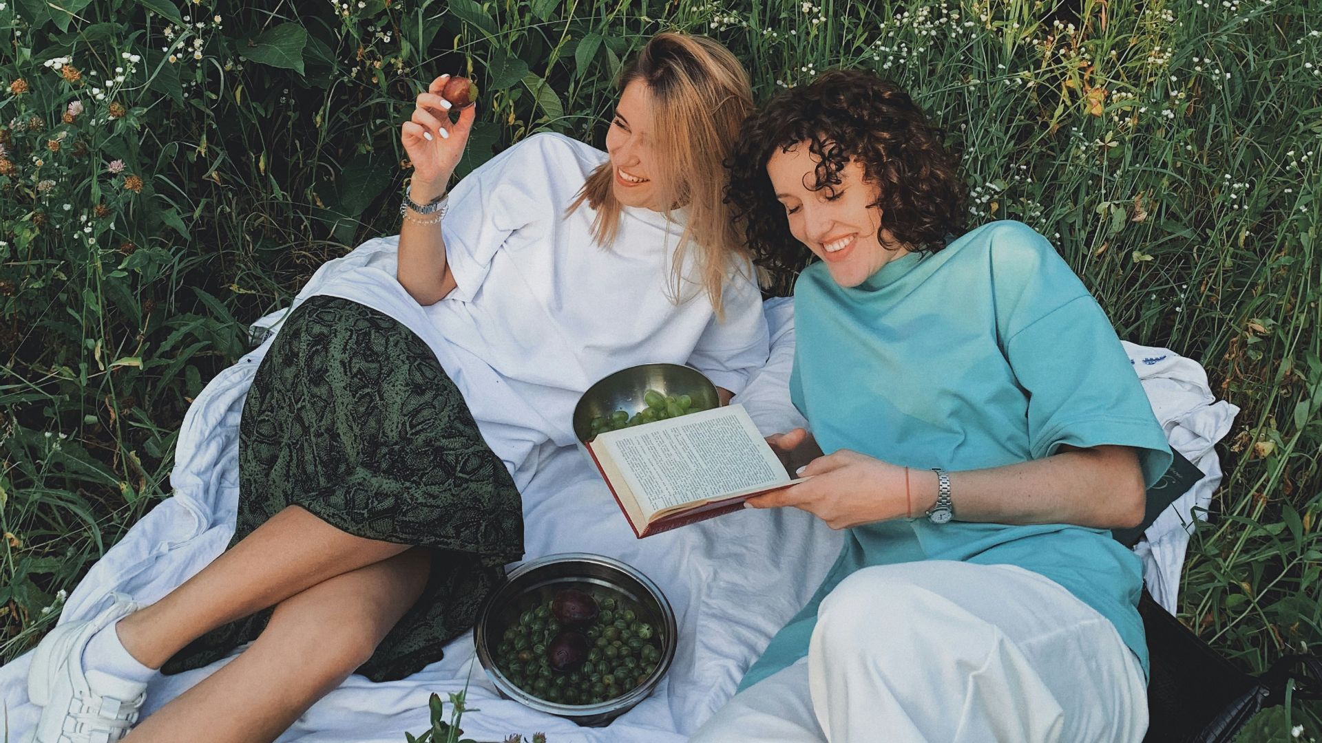 man and woman sitting on white bed reading book