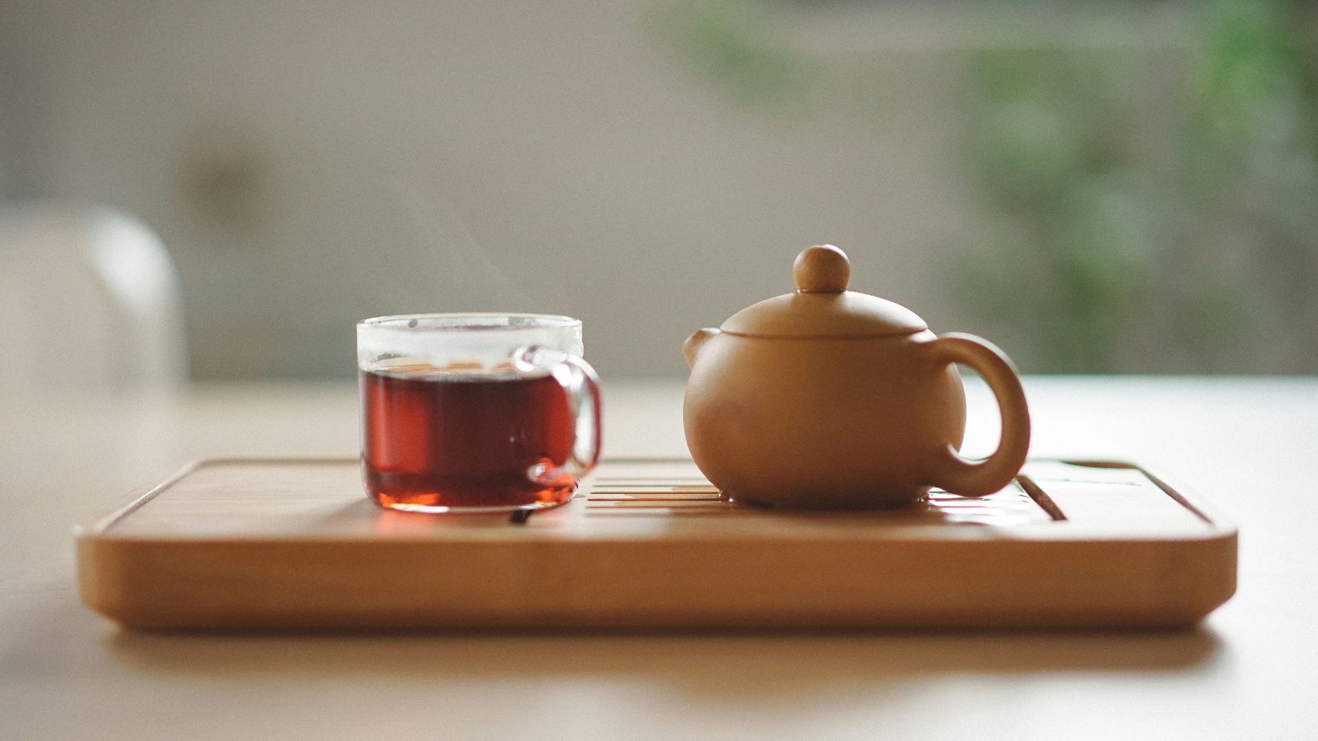 clear glass cup with tea near brown ceramic teapot