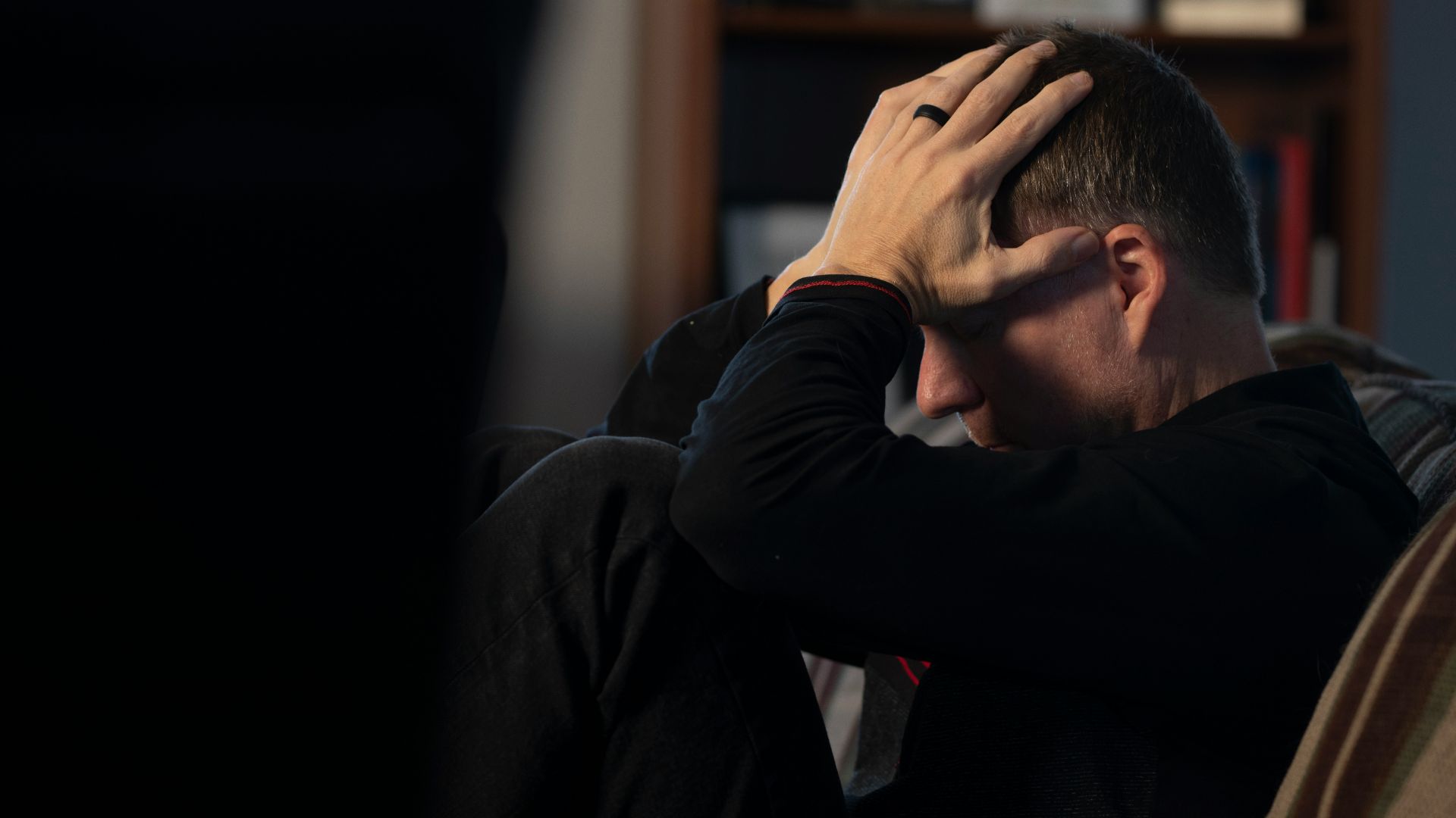 a man sitting on a couch holding his head in his hands