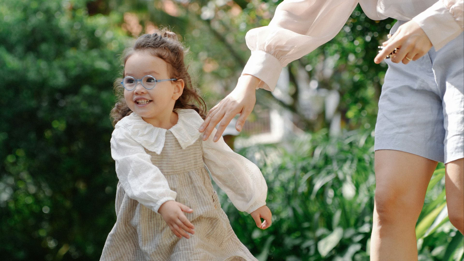 A young girl with a parent in a park