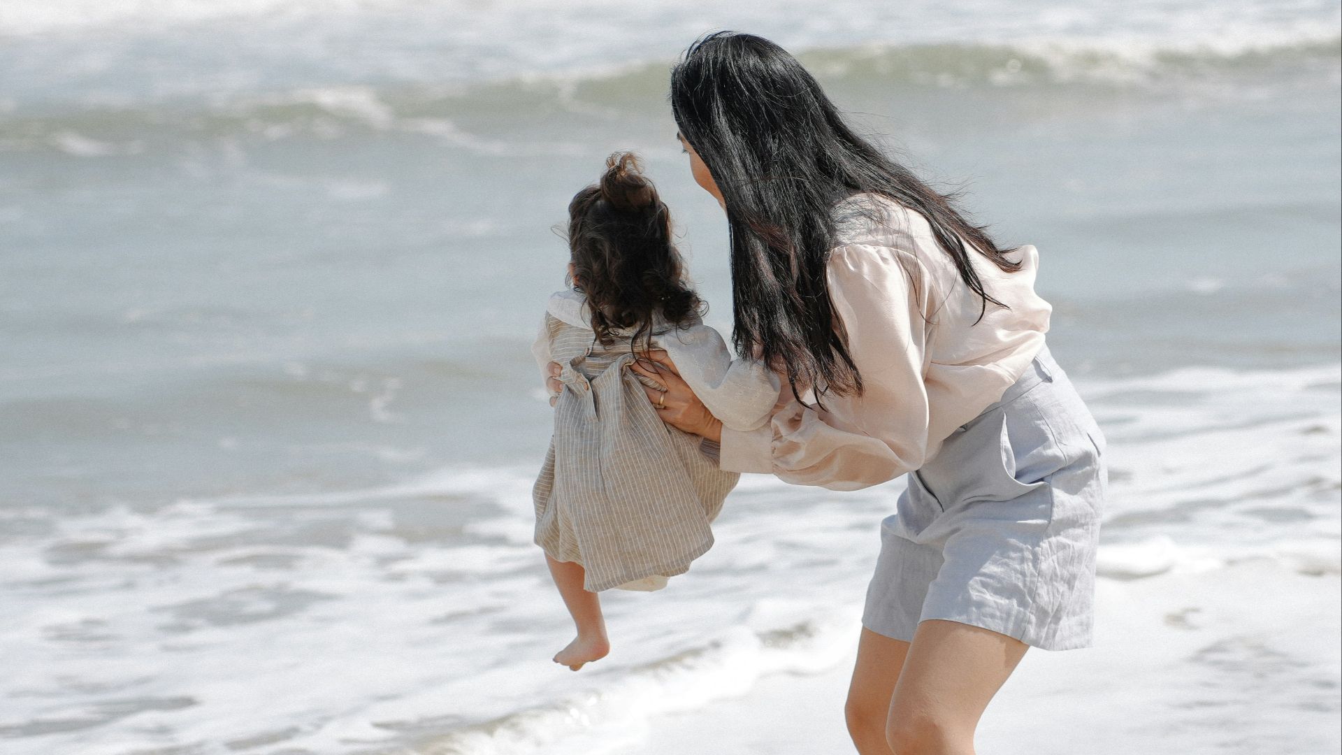 Mother and child playing in the ocean waves