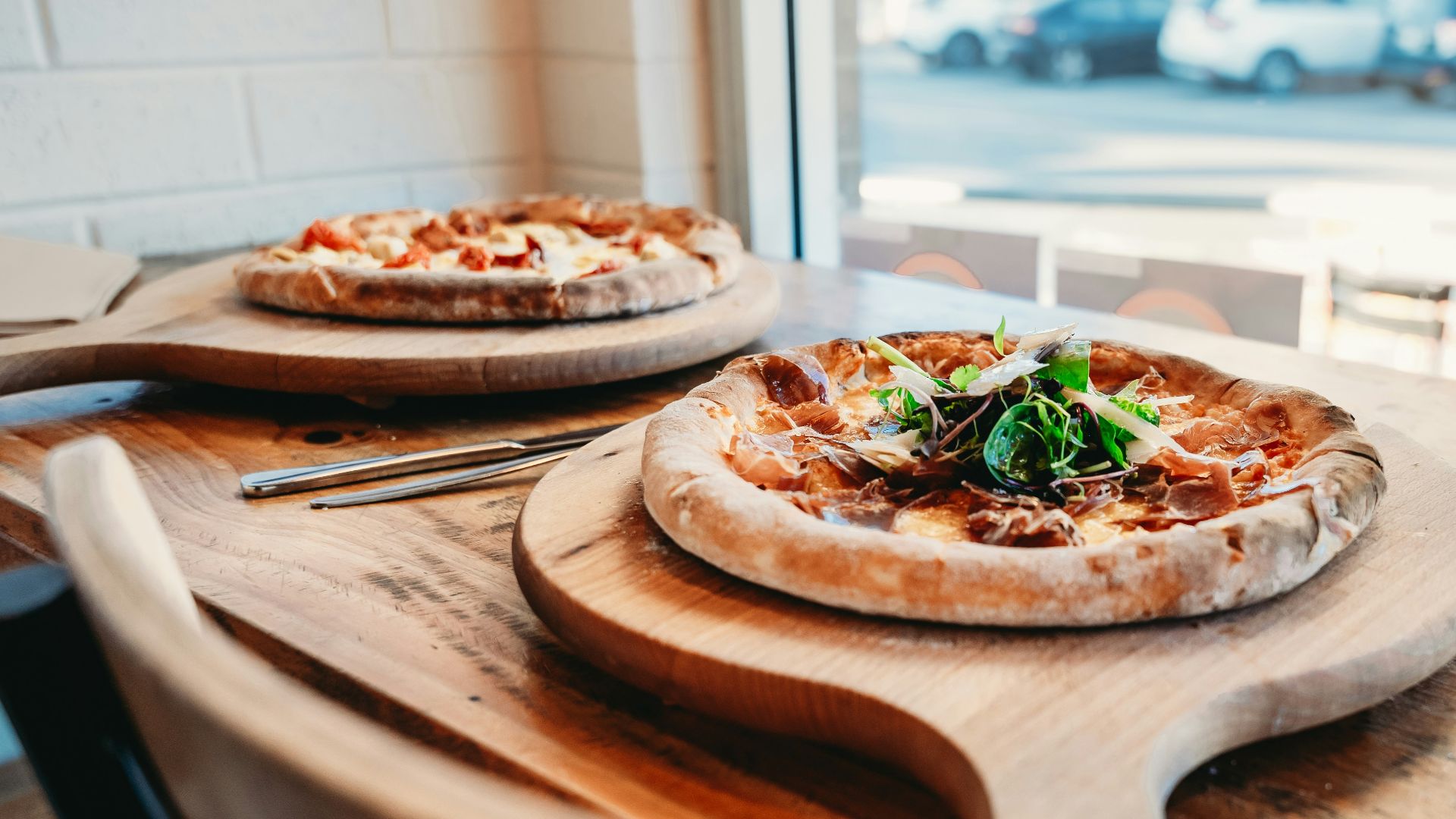 Two pizzas with a glass of red wine.