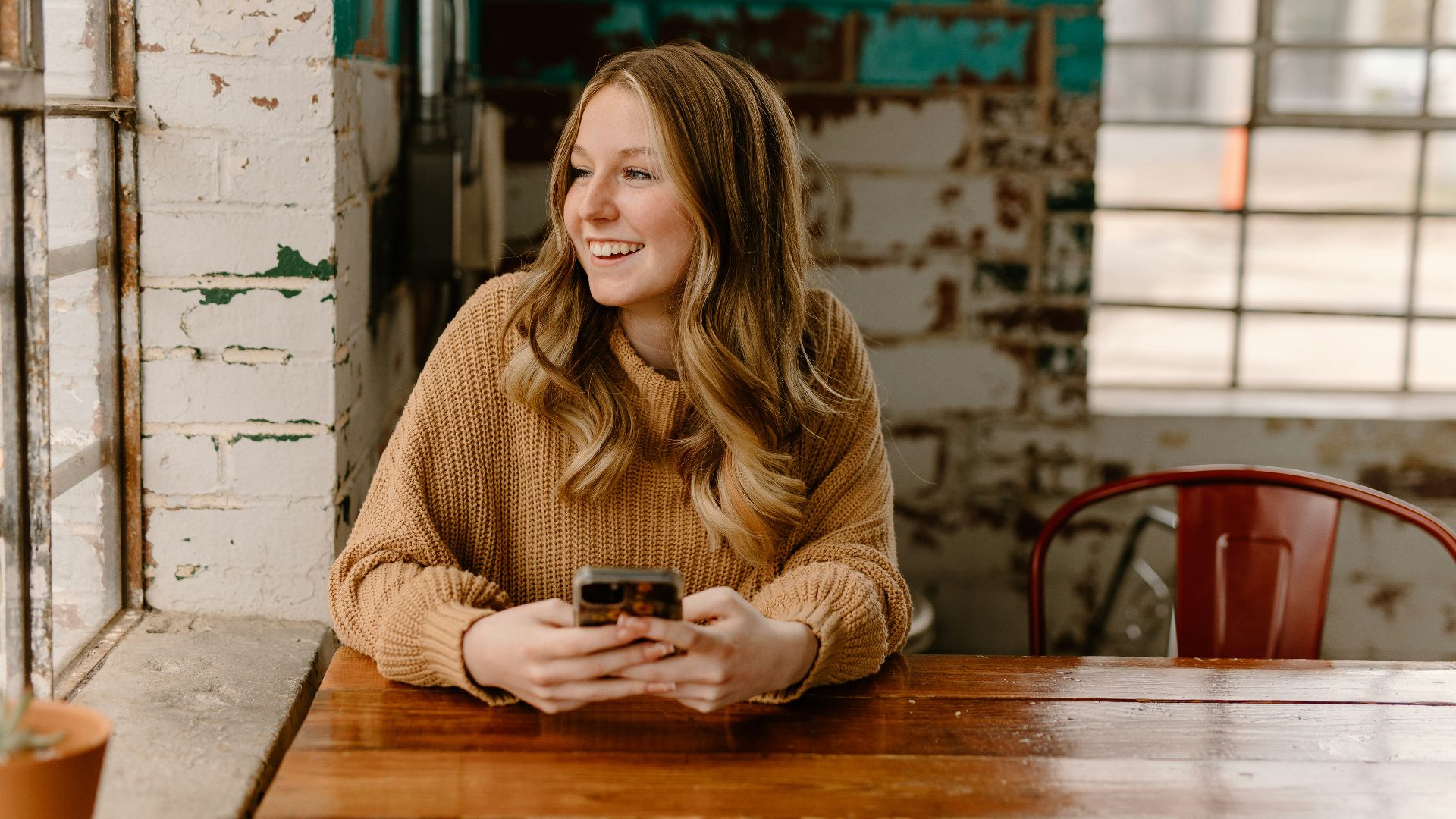 a woman sitting at a table with a cell phone
