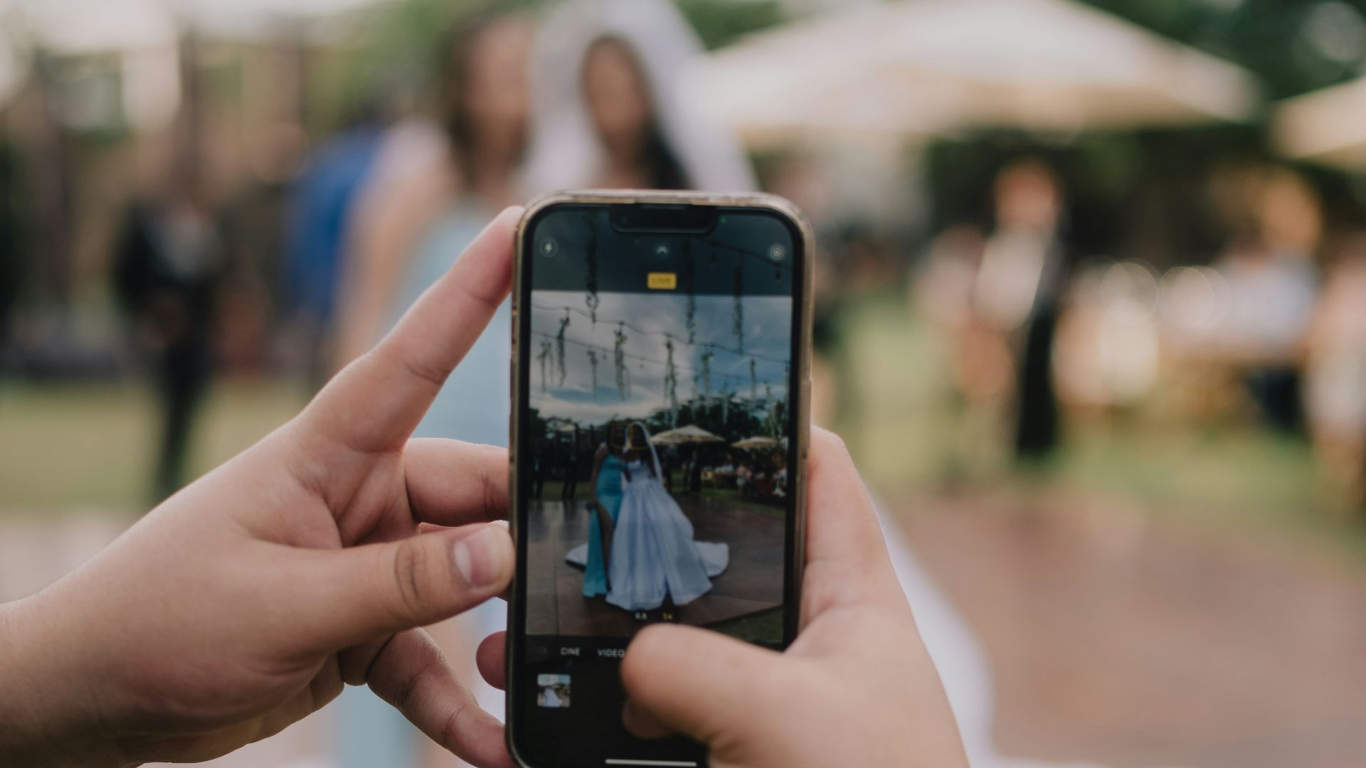 Hands holding phone taking picture of bride