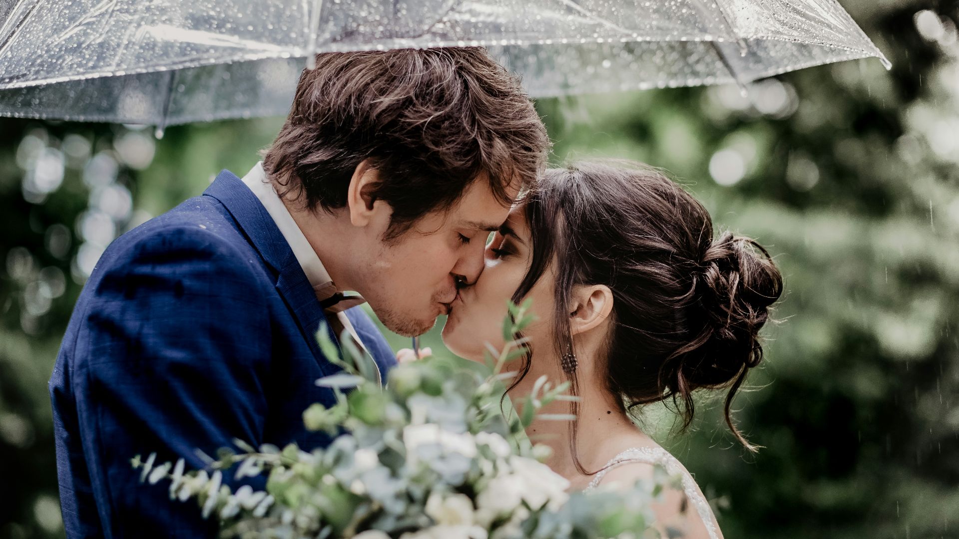 man in blue suit kissing woman in white floral dress