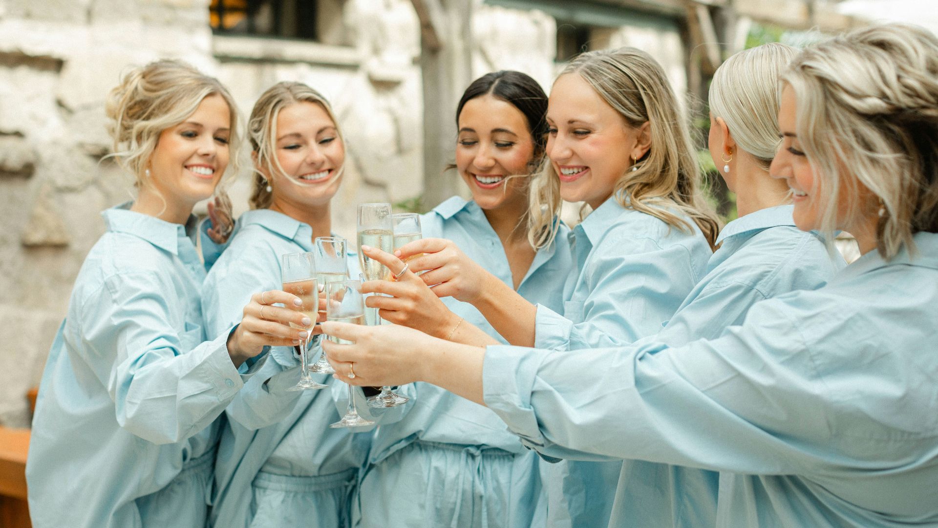 a group of women standing around each other holding wine glasses