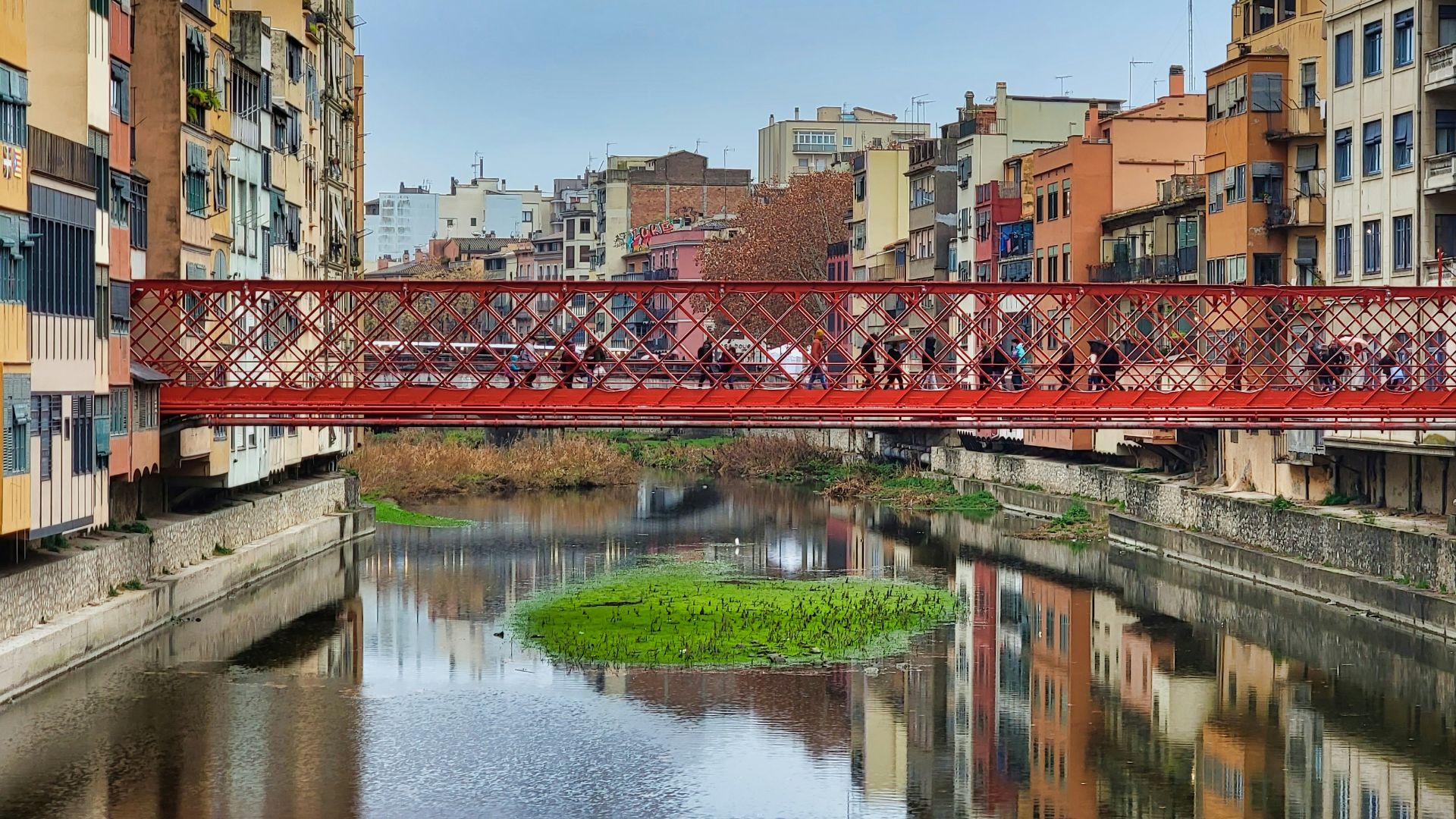 a red bridge over a river in a city
