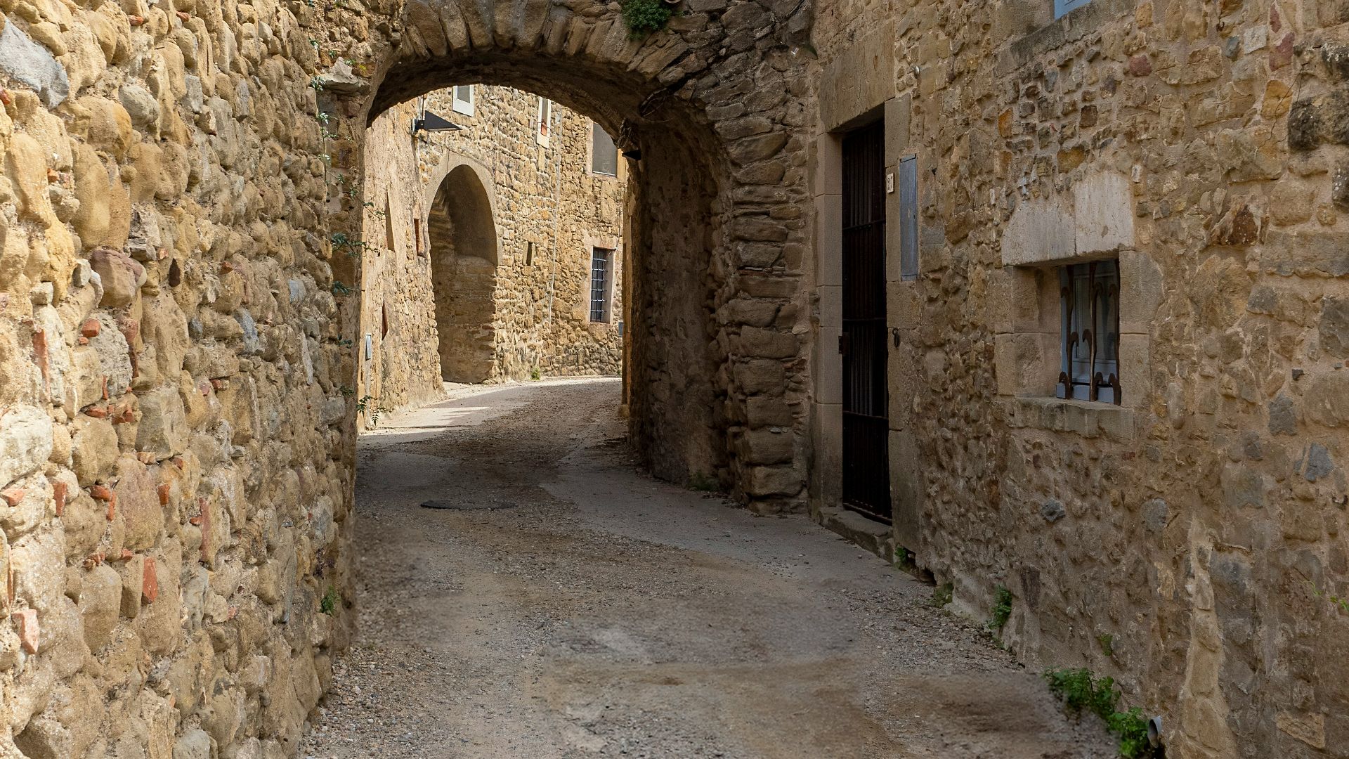 A narrow alley with a stone building and a clock tower