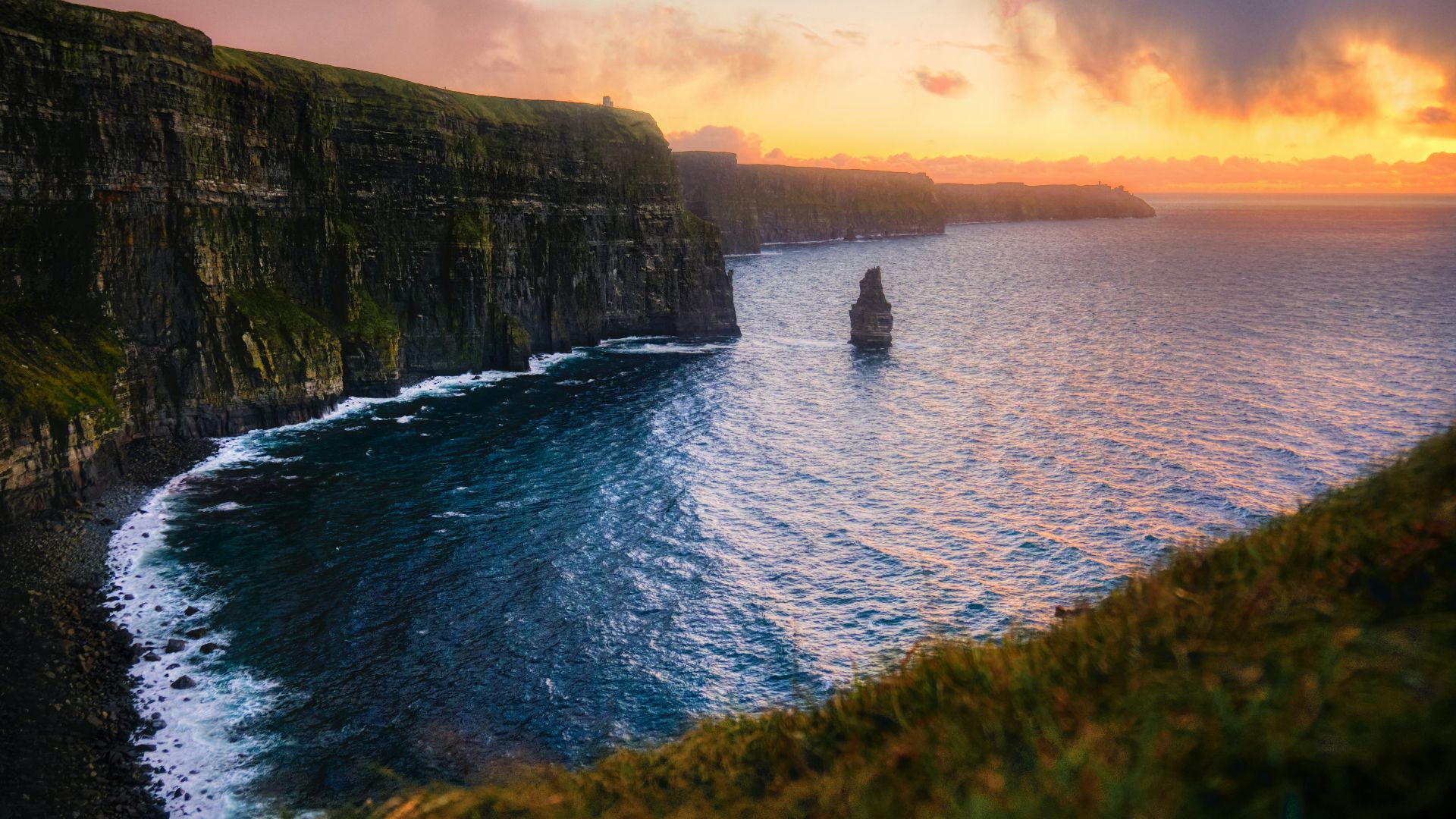 green and brown mountain beside body of water during sunset