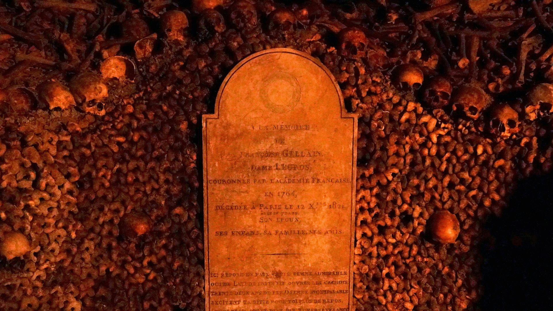 A tombstone stands amidst skulls and bones.