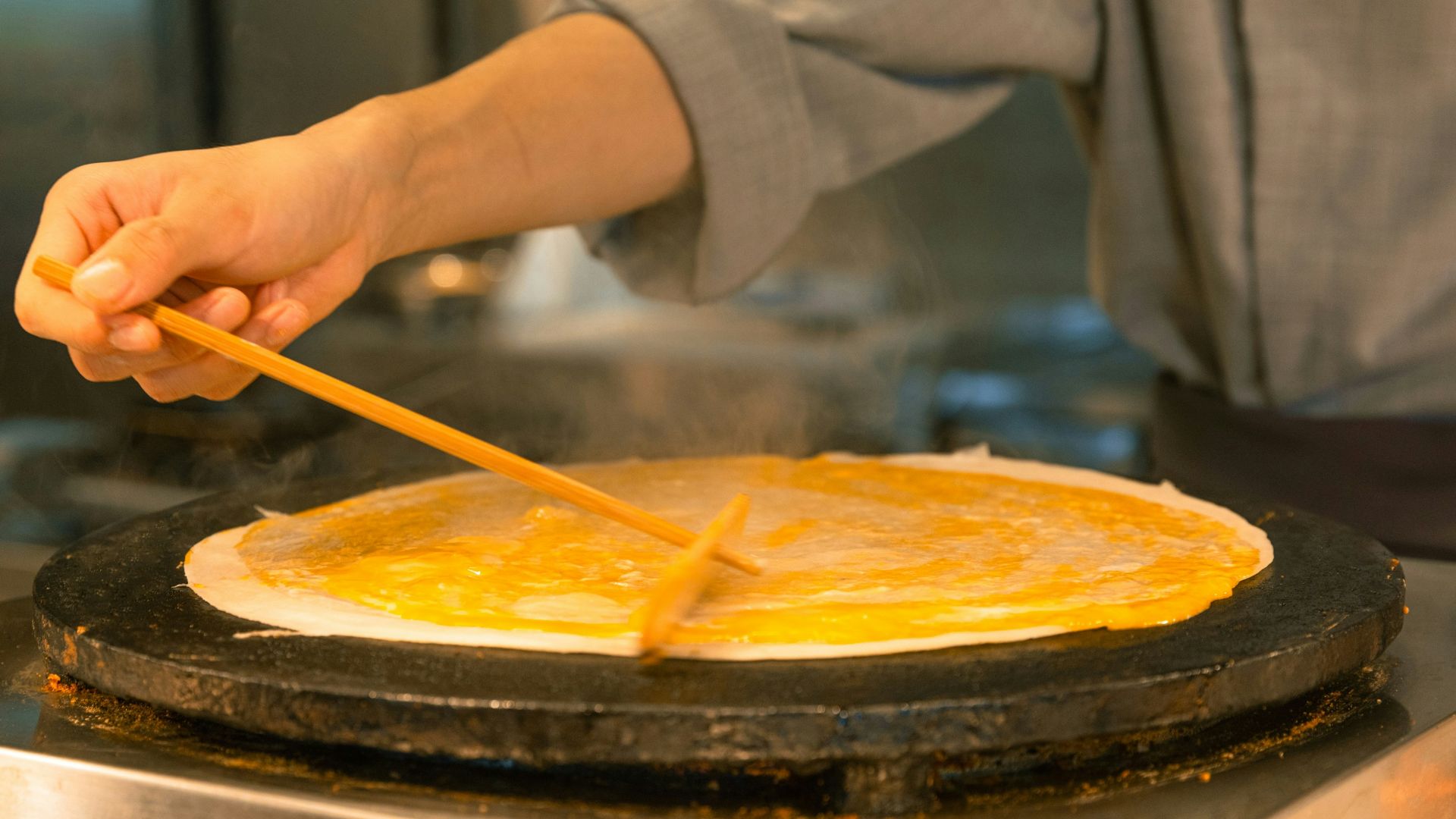 A person cooking pancakes in a pan on a stove