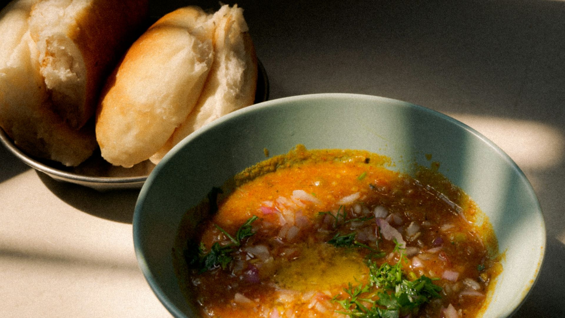 a bowl of soup next to a bowl of bread