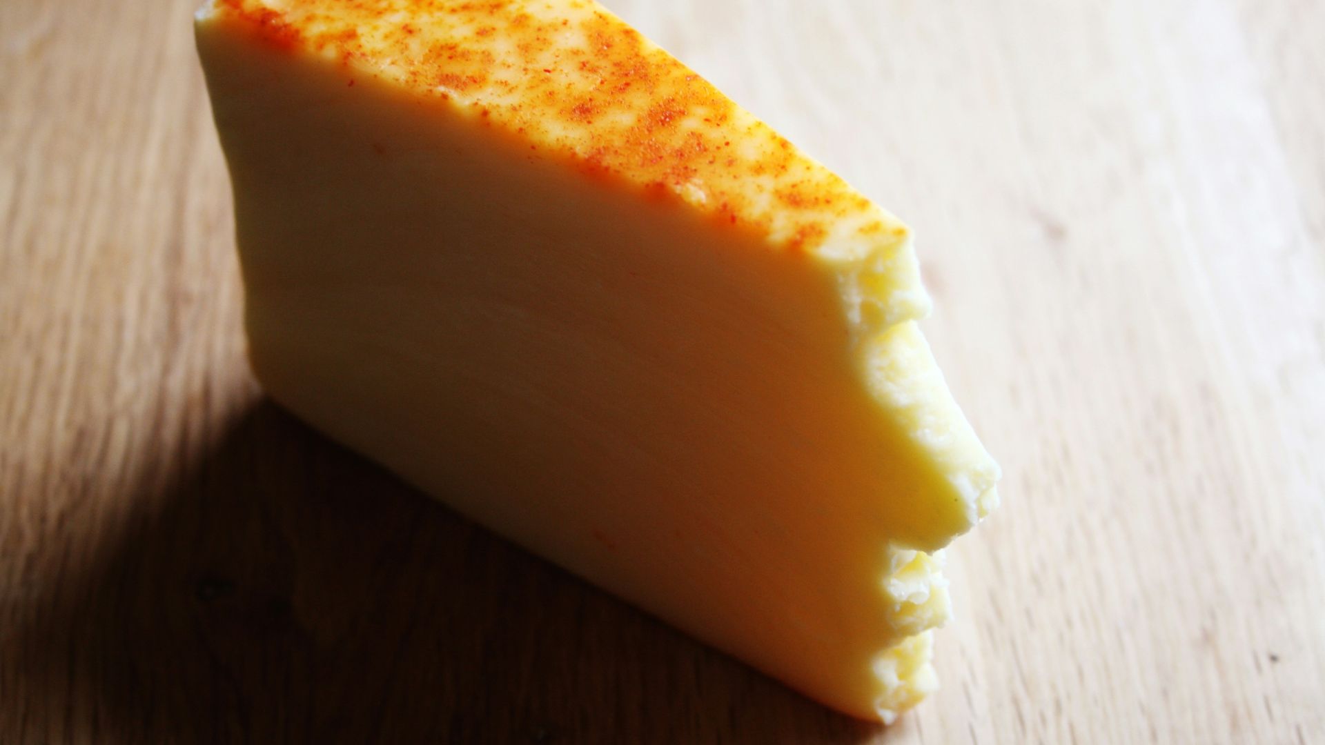 A piece of cheese sitting on top of a wooden table