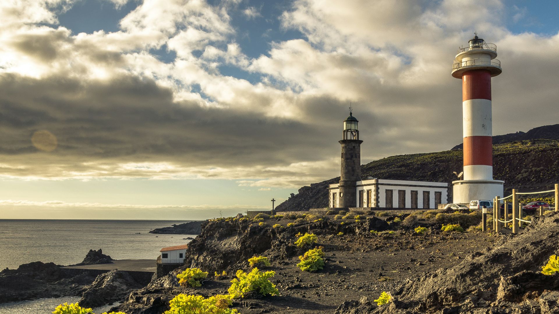 white and red lighthouse on rocky hill near sea under cloudy sky during daytime