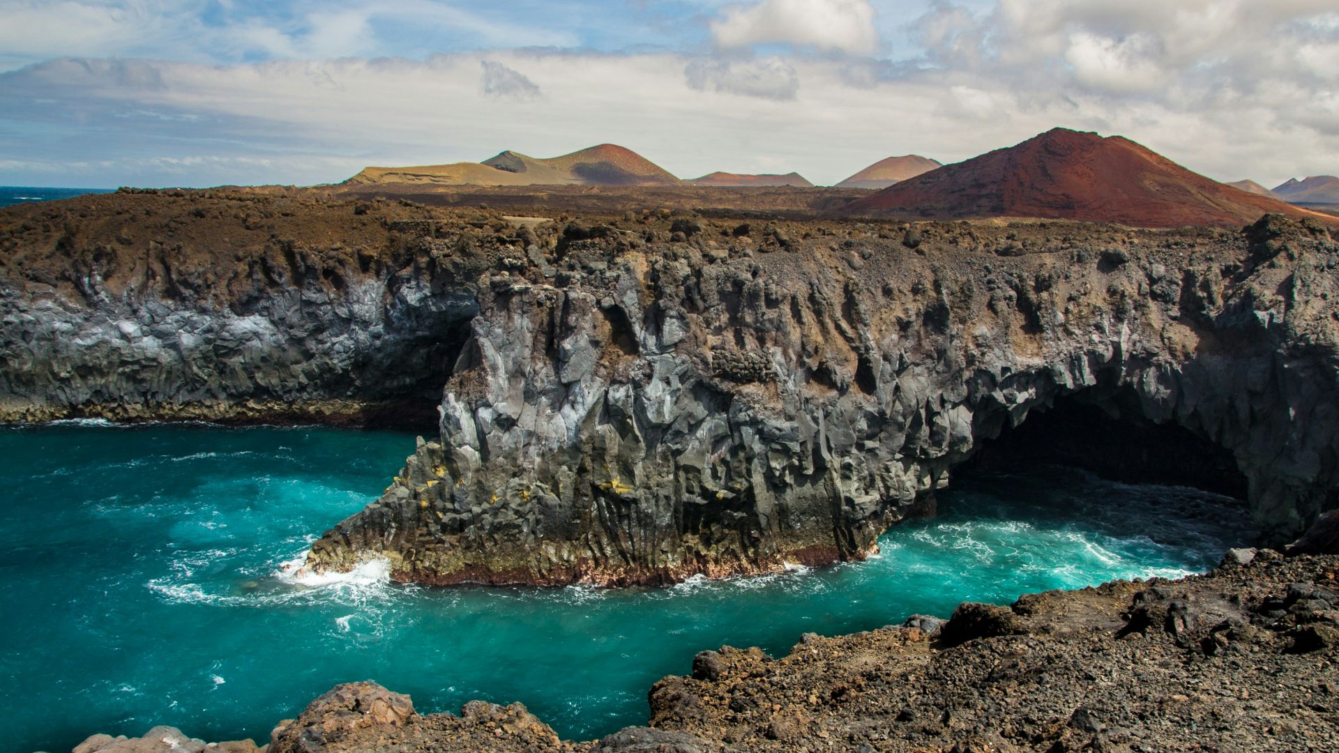 brown rocky mountain beside blue sea under blue sky during daytime