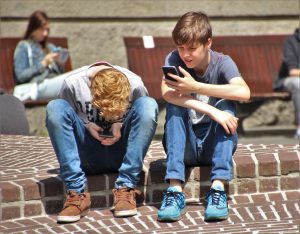 2-boy-sitting-on-brown-floor-while-using-their-smartphone-159395-2-300x234.jpg
