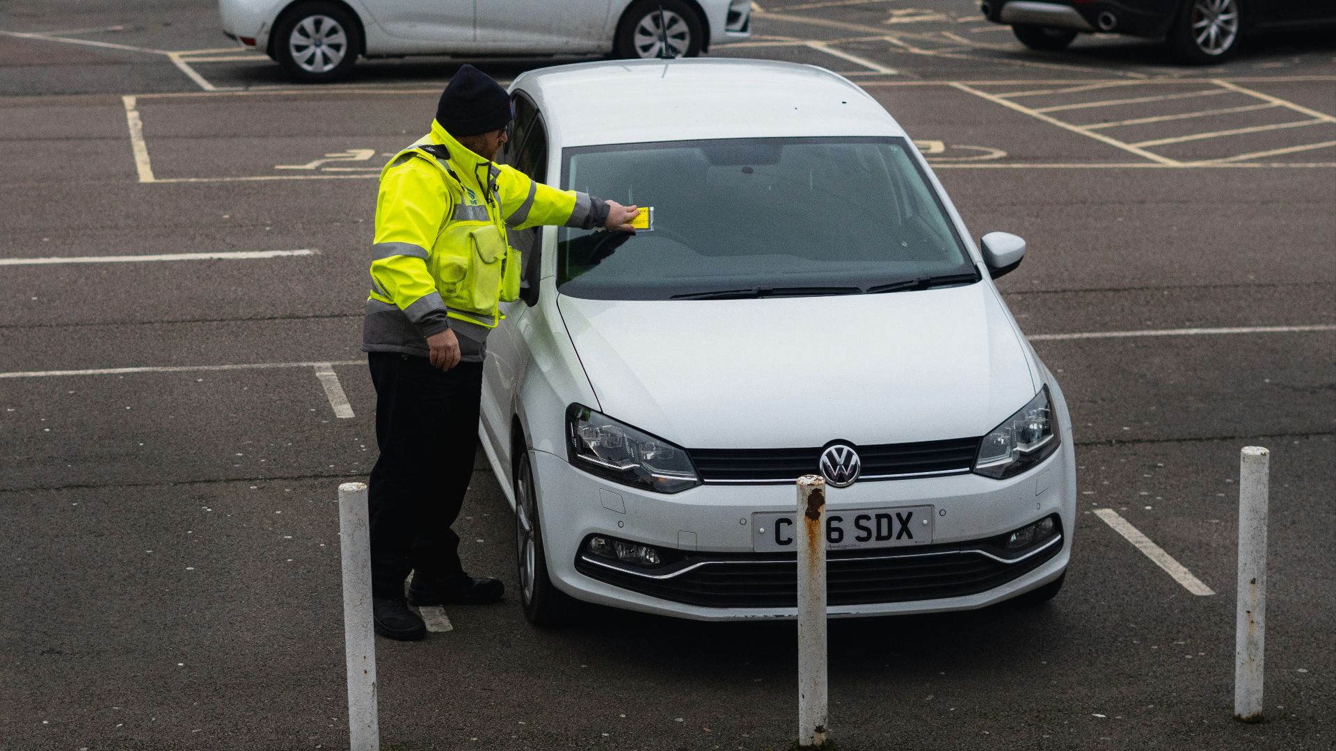 man in yellow jacket standing beside white car